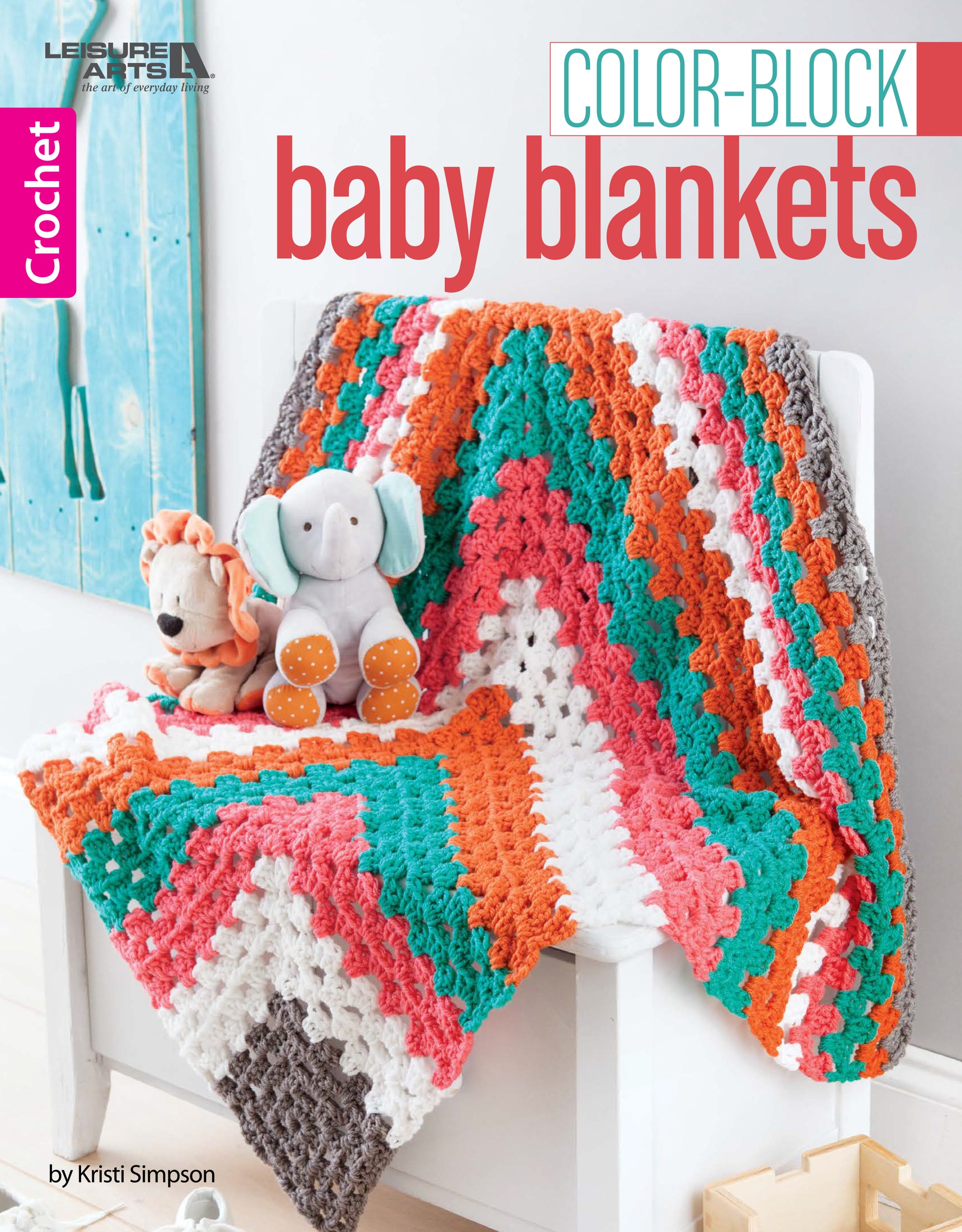 The Leisure Arts Color-Block Baby Blankets, featuring vibrant zigzag stripes in orange, teal, white, and gray, is draped over a white chair with plush lion and elephant toys—ideal for cozy nursery decor.