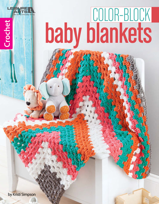 The Leisure Arts Color-Block Baby Blankets, featuring vibrant zigzag stripes in orange, teal, white, and gray, is draped over a white chair with plush lion and elephant toys—ideal for cozy nursery decor.
