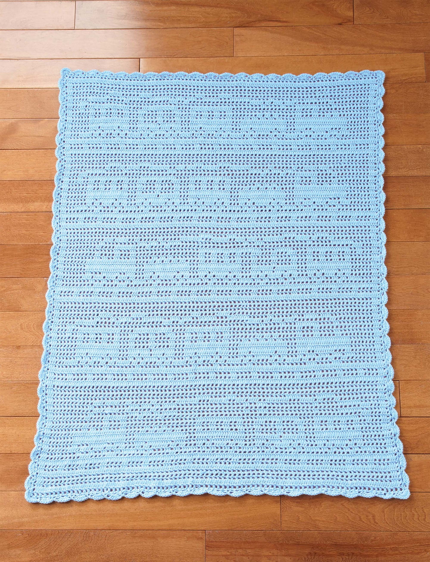 The Cuddle Me Baby Afghans by Leisure Arts is a light blue crocheted baby blanket with a train and track pattern, scalloped border, and an intermediate design—perfect as a baby shower gift or for those wanting unique baby blanket patterns.