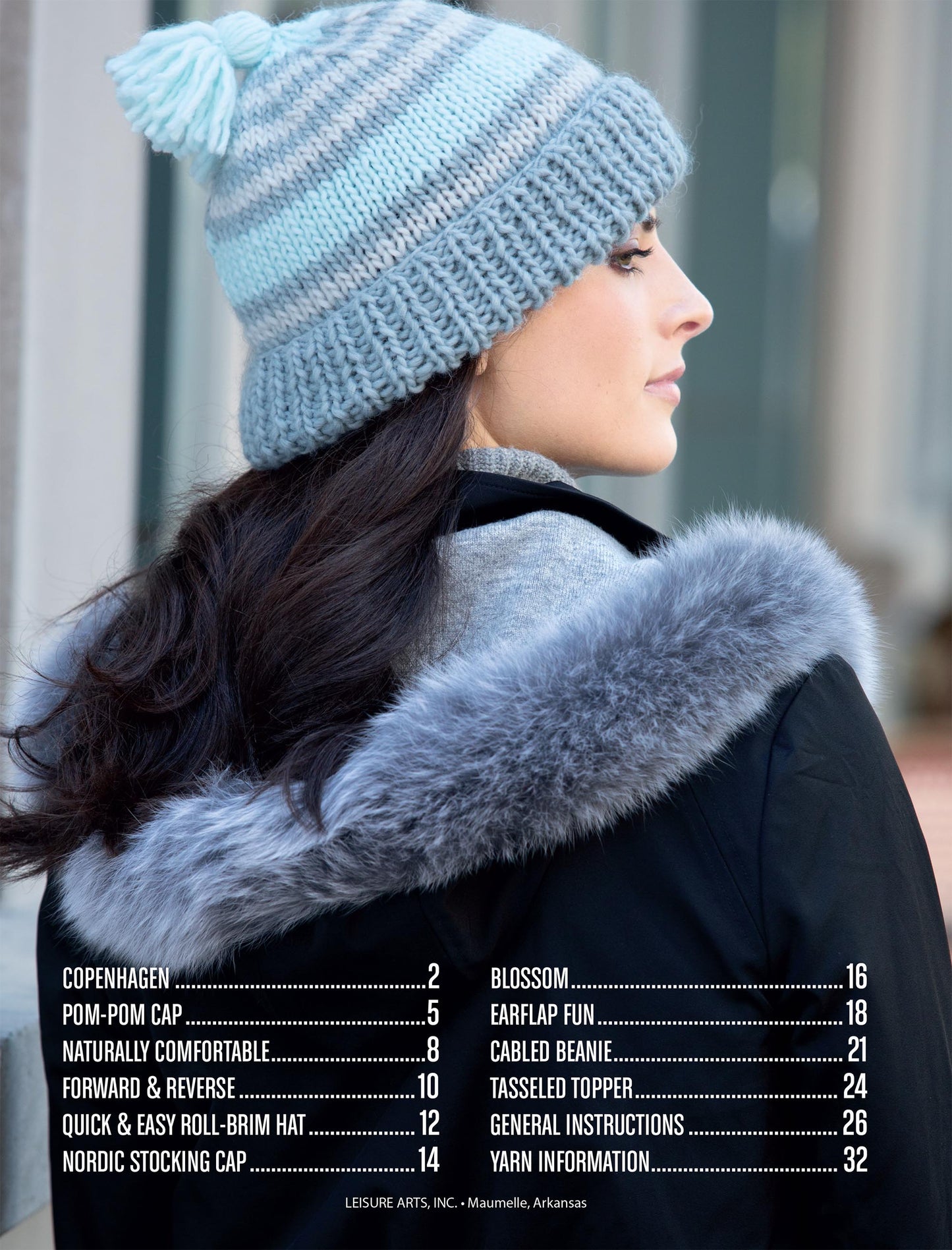 A woman in a light blue and white knit pom-pom hat and a black faux fur hooded coat stands outside. "Hats for the Family" by Leisure Arts displays knitting patterns and project names with page numbers at the image's bottom.