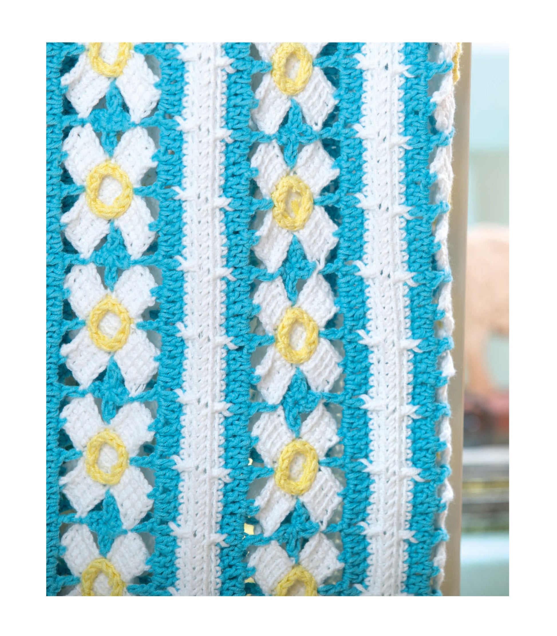 Close-up of Baby Bright Quilts by Leisure Arts, featuring white and yellow flower crochet patterns in vertical rows on turquoise blue—ideal for beginner crocheters or stunning, colorful baby blankets.