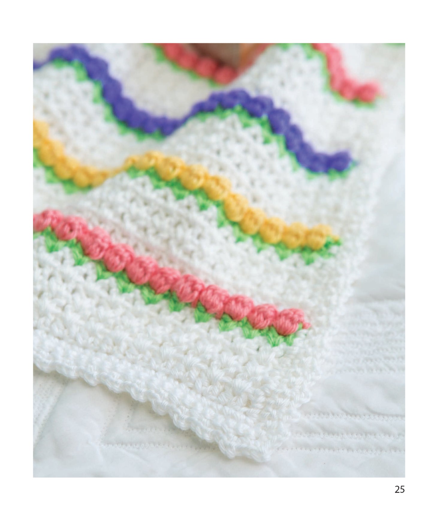 A close-up of the Leisure Arts Baby Bright Quilts displays beginner-friendly crochet patterns with colorful wavy rows in purple, yellow, pink, and green on a white quilted background.