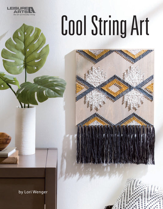 The cover of Cool String Art by Leisure Arts displays geometric string art made with gold, white, and black thread on a board, mounted above a wooden table with a white vase and plant.