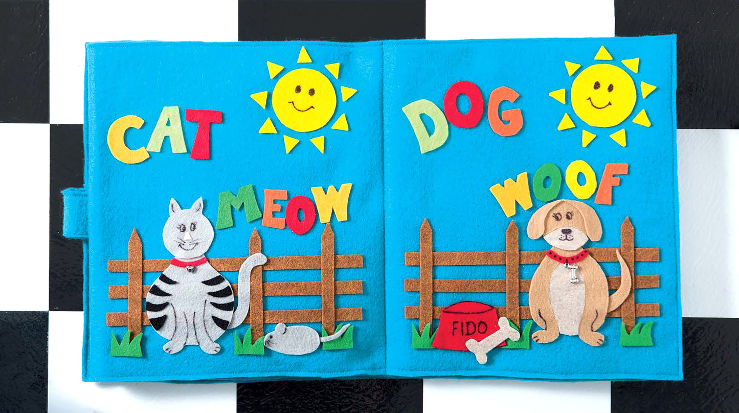 The Make Your Own Quiet Book by Leisure Arts features felt pieces to create a cat with "CAT" and "MEOW" on one page, and a dog with "DOG," "WOOF," his bone, bowl labeled Fido, plus a barn and silo on the other—all under a sunny sky.