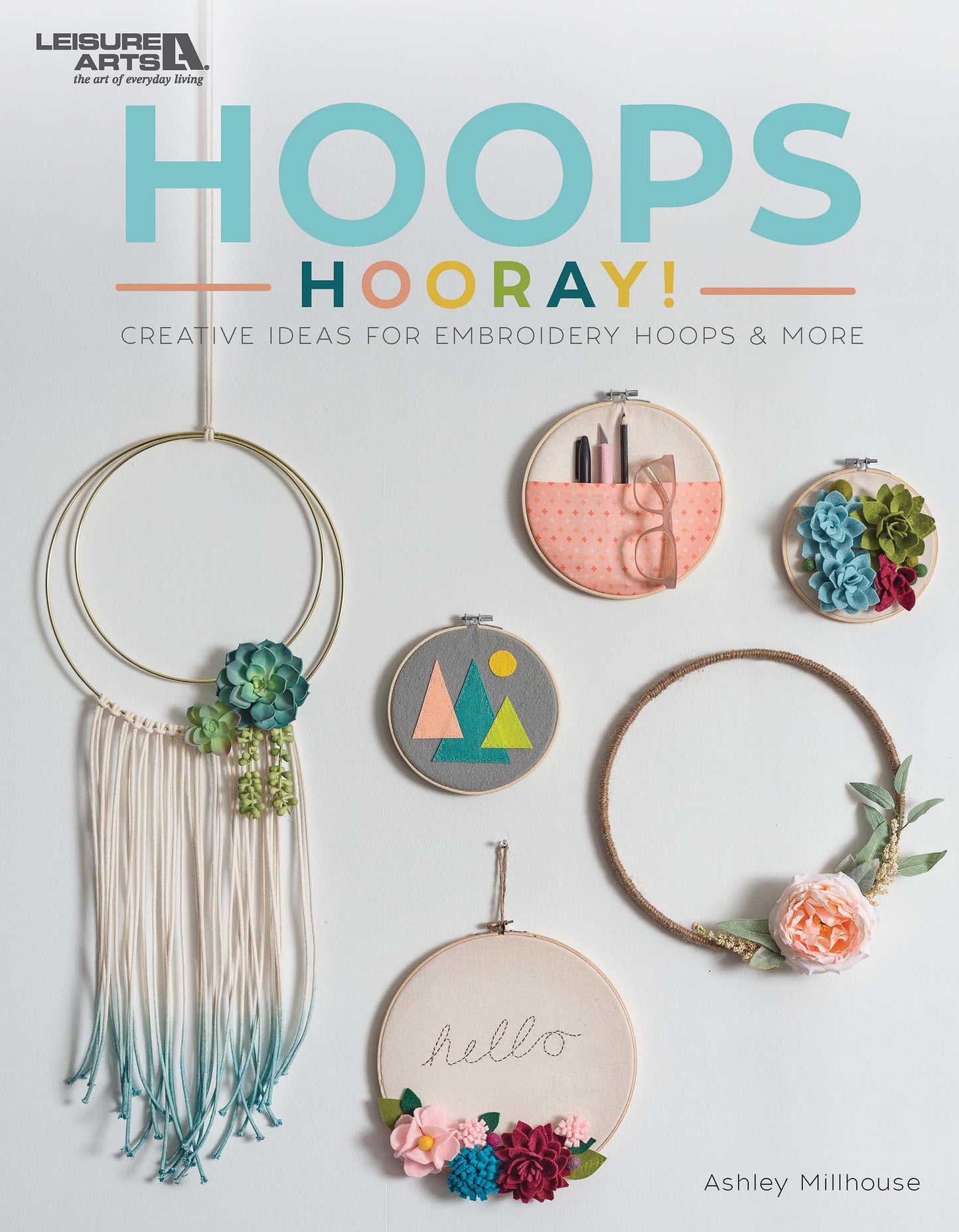 Six artistic embroidery hoops feature yarn, flowers, geometric trees, and fabric pockets. The cover reads: Hoops Hooray! Creative Ideas for Embroidery Hoops & More. Product: Hoops Hooray! Digital Download by Leisure Arts.