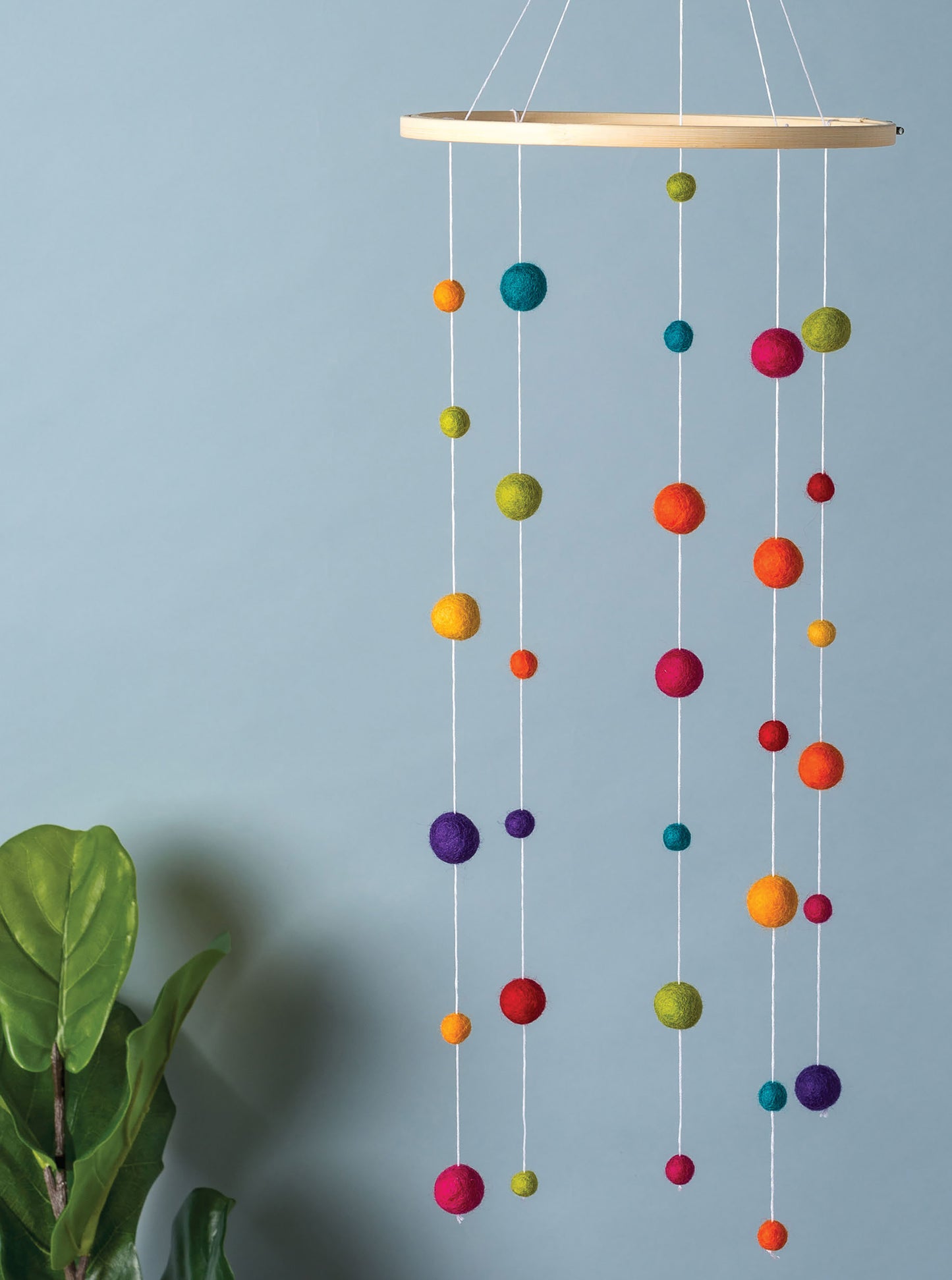 The Hoops Hooray! Digital Download by Leisure Arts features a hanging mobile crafted from colorful felt balls in various sizes, suspended on white strings from an embroidery hoop, with a leafy green plant and a light blue background.