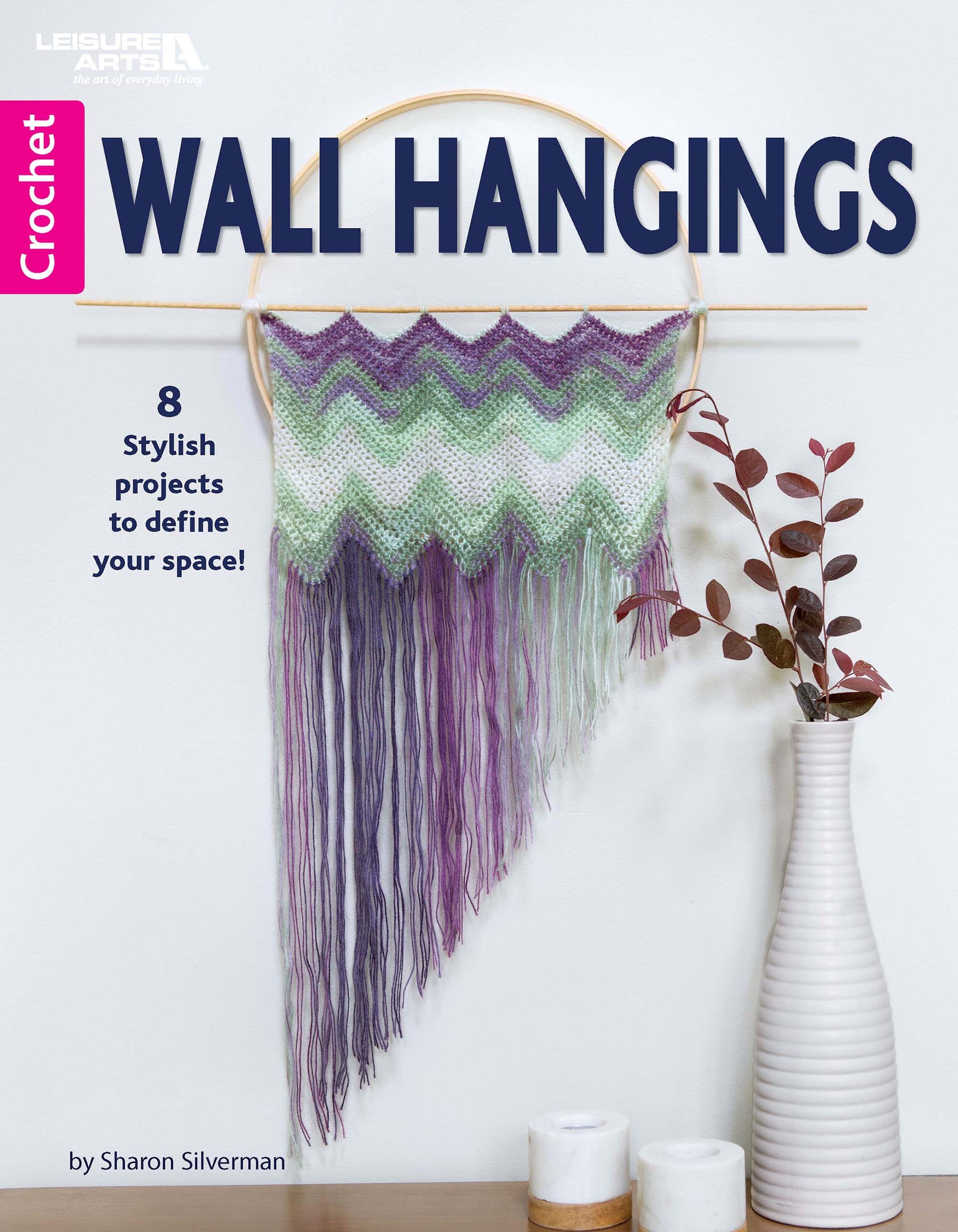 Cover of Leisure Arts' digital download, Wall Hangings—8 Stylish Projects to Define Your Space!, featuring a purple, green, and white crochet wall hanging on a dowel, a white vase with branches, and the tagline “8 stylish crochet patterns to define your space!”.