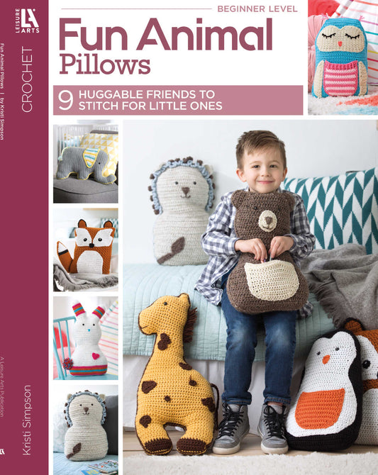 Cover of Leisure Arts’ book, "Fun Animal Pillows—9 Huggable Friends to Stitch for Little Ones." A smiling boy on a couch holds a bear pillow, surrounded by animal pillows shaped like a fox, giraffe, bunny, and owl.