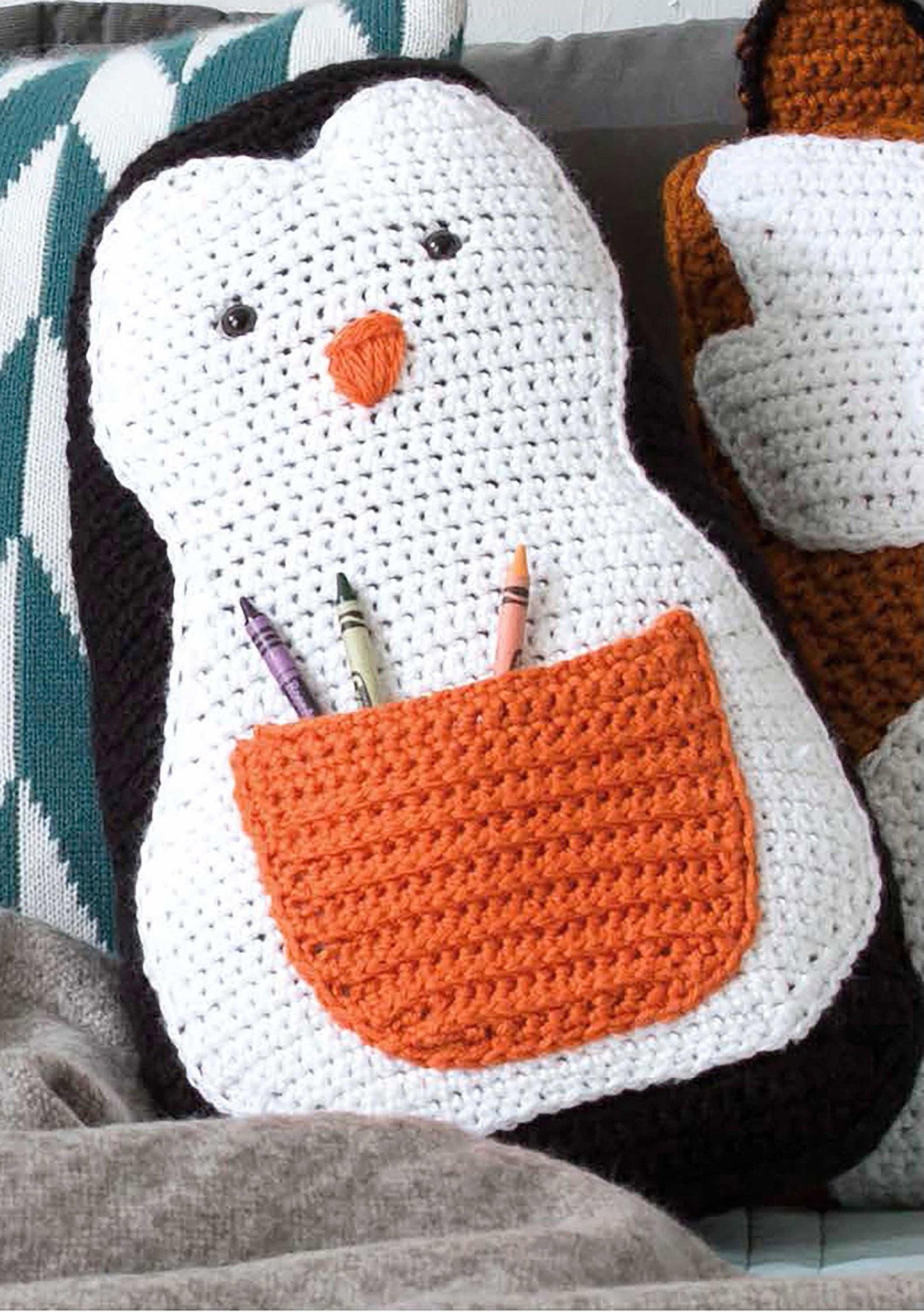 Leisure Arts’ Fun Animal Pillows—9 Huggable Friends to Stitch for Little Ones features adorable crochet designs like a penguin with a white face, black outline, orange beak, and crayon pocket—perfect for animal-shaped pillow fans.