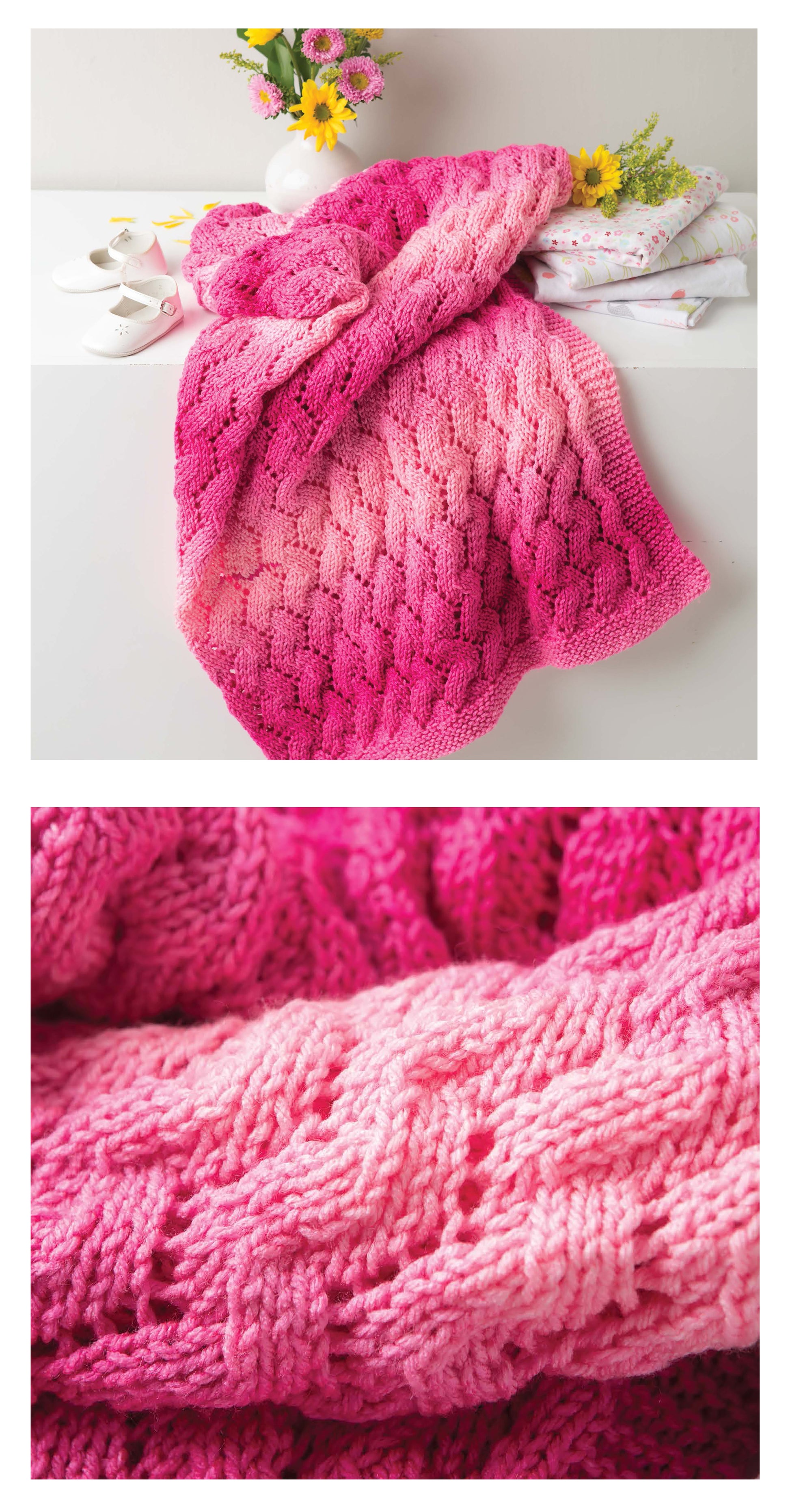 The Leisure Arts "Make Your First Knit Baby Afghan," a pink ombre cable-knit blanket ideal for beginners, is displayed with white baby shoes, floral fabric, and yellow-pink flowers. Close-up highlights the textured stitches.