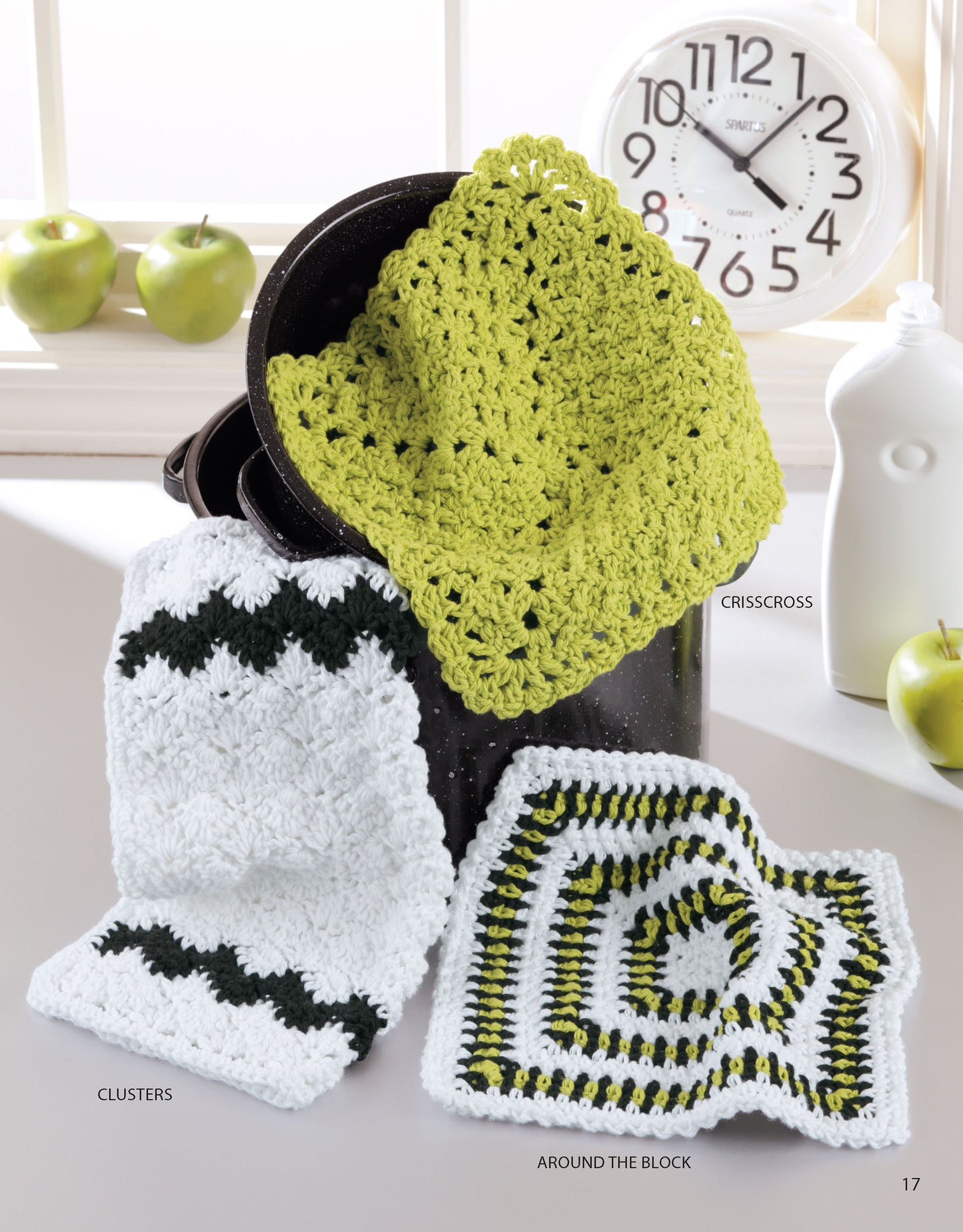 Quick & Colorful Dishcloths Designs to Brighten Any Kitchen by Leisure Arts features three crochet cloths—green, white with green accents, and striped—displayed on a black pot. These beginner patterns are perfect quick gifts to add charm to your kitchen.
