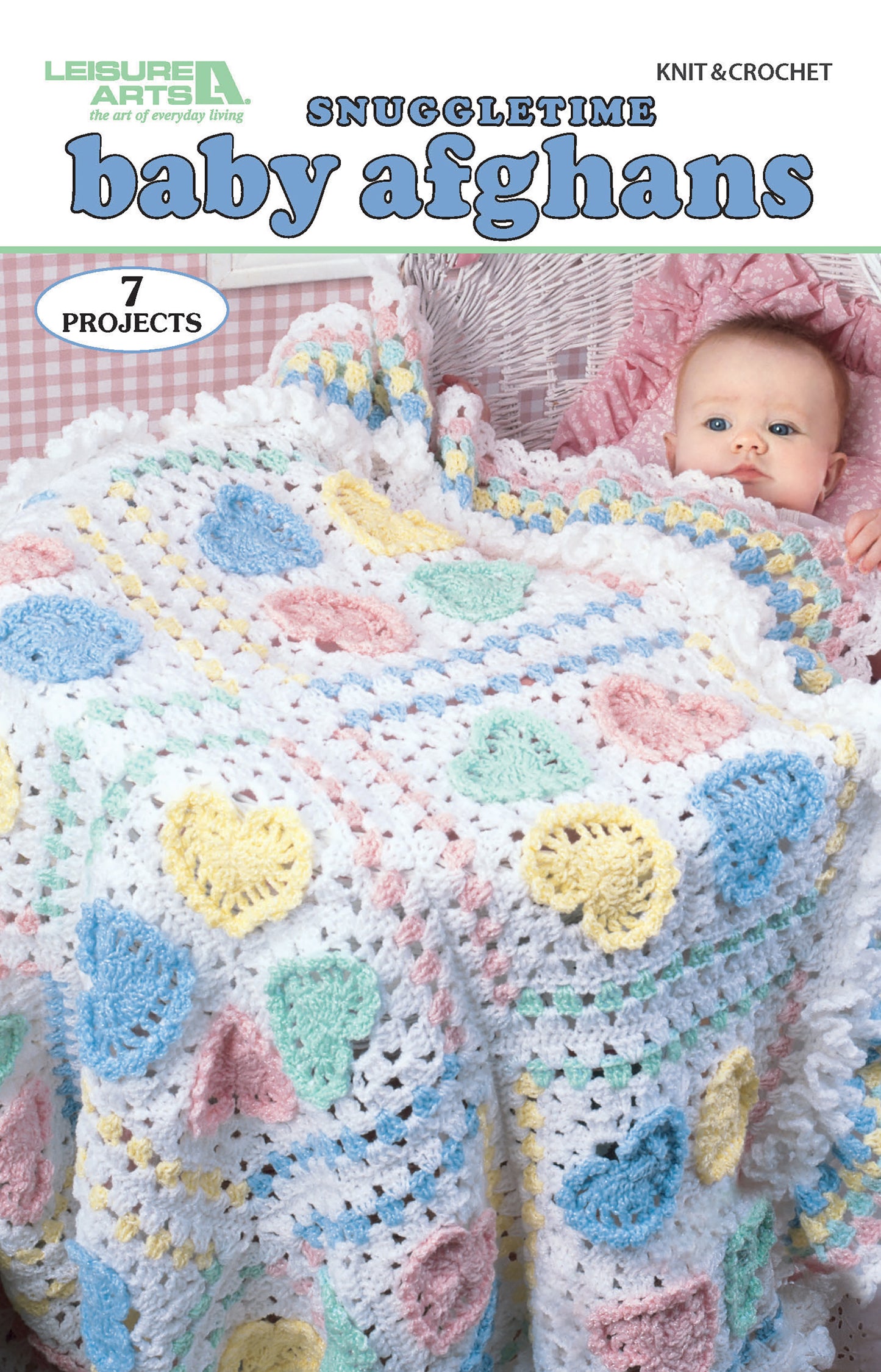 The Leisure Arts Snuggletime Baby Afghans booklet features 7 baby throw patterns. The cover shows a baby in a wicker bassinet with a white crochet afghan decorated with pastel heart motifs.
