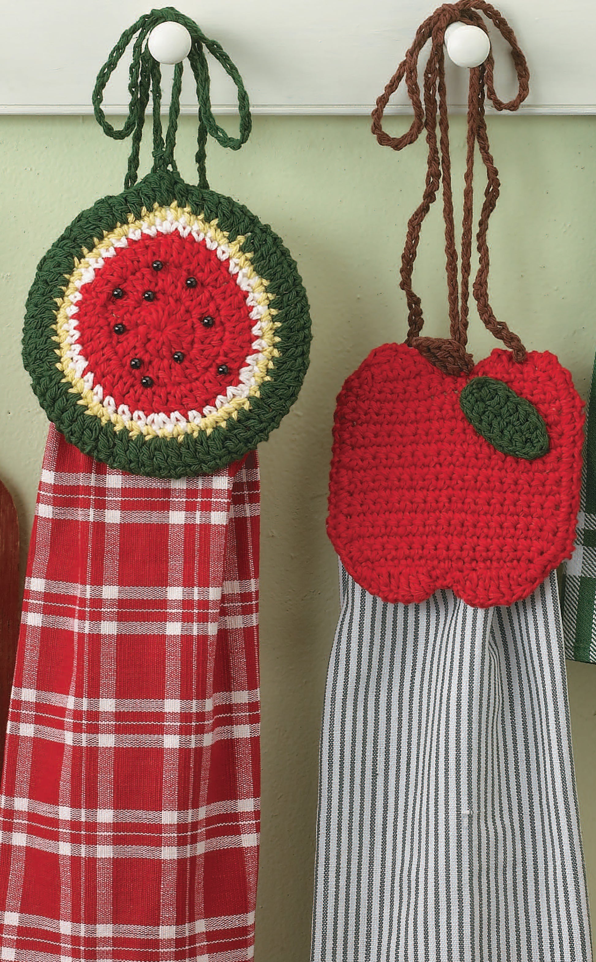 Leisure Arts’ Little Kitchen Helpers features two crochet towel holders—one watermelon, one apple—hanging on white hooks with red plaid and gray striped dishcloths. These charming patterns make perfect kitchen gifts.