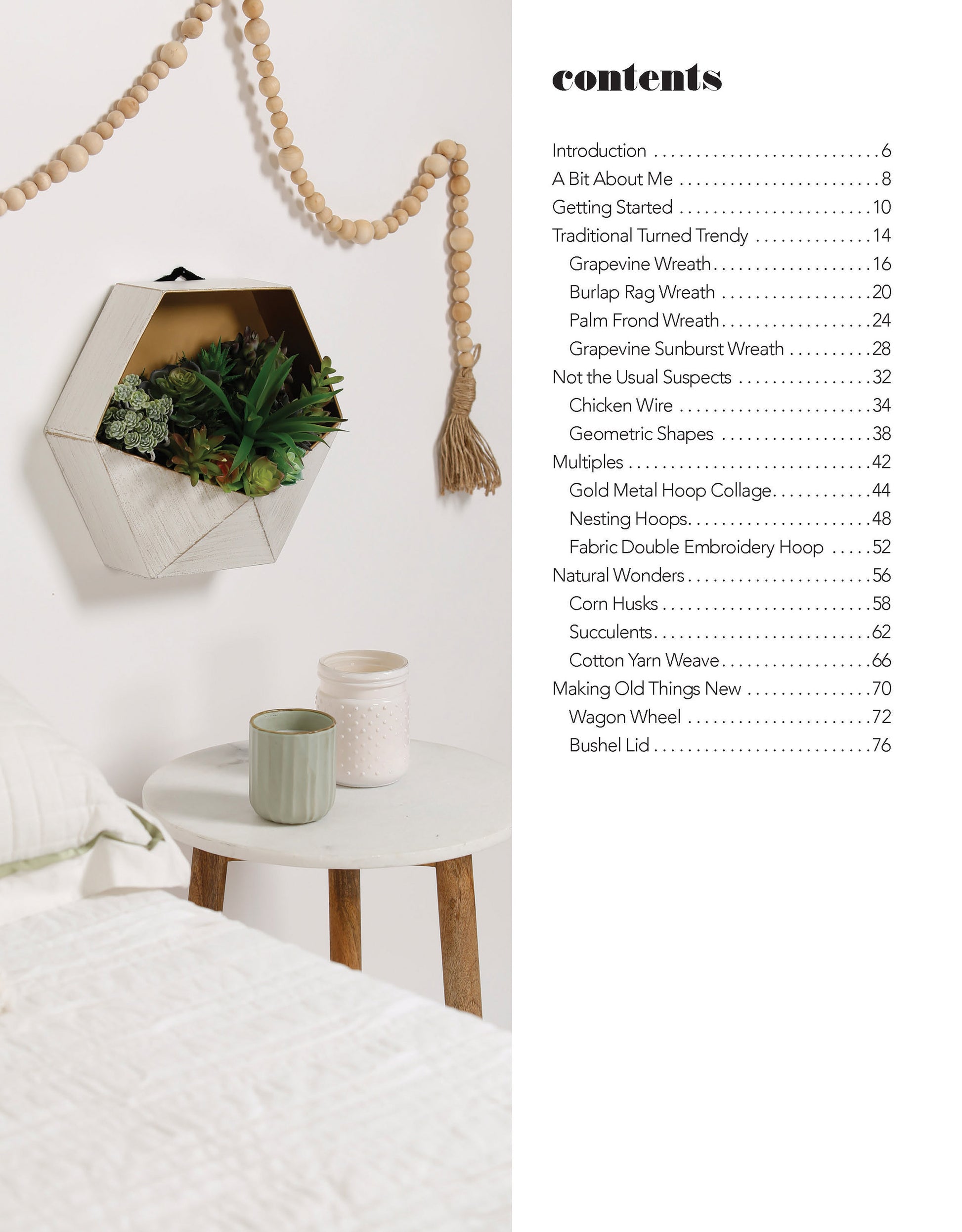 A small bedside table with three ceramic cups and a candle sits by the bed. Above, a hexagonal wall planter and wooden bead garland add DIY style—perfect inspiration from Leisure Arts’ Quick Wreath Designs Digital Download. Contents listed on right.
