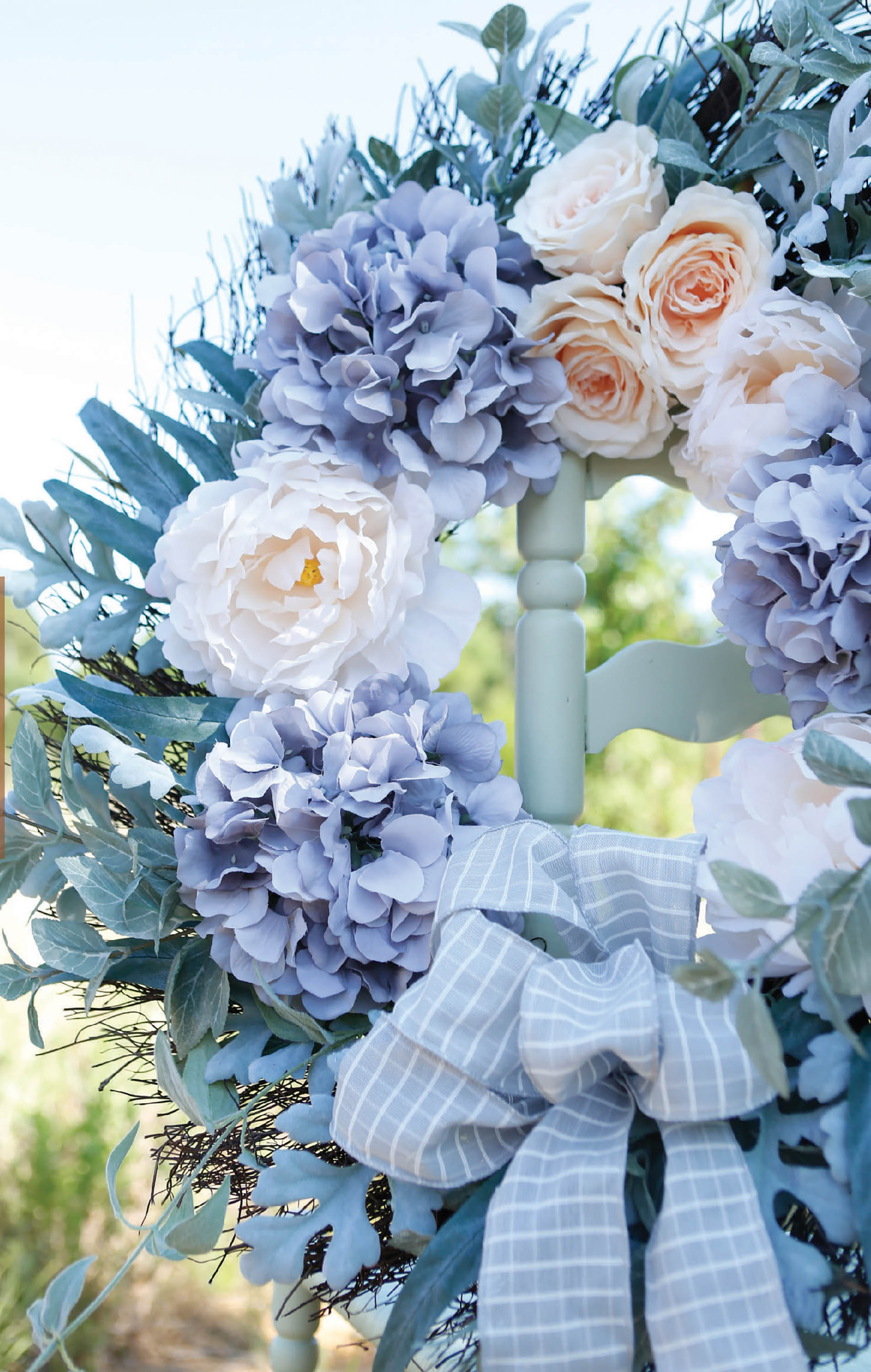 Quick Wreath Designs Digital Download by Leisure Arts features a pale blue, lavender, and cream artificial flower wreath with green foliage and a gray plaid bow—ideal inspiration for home decor crafts or beginner DIY projects.