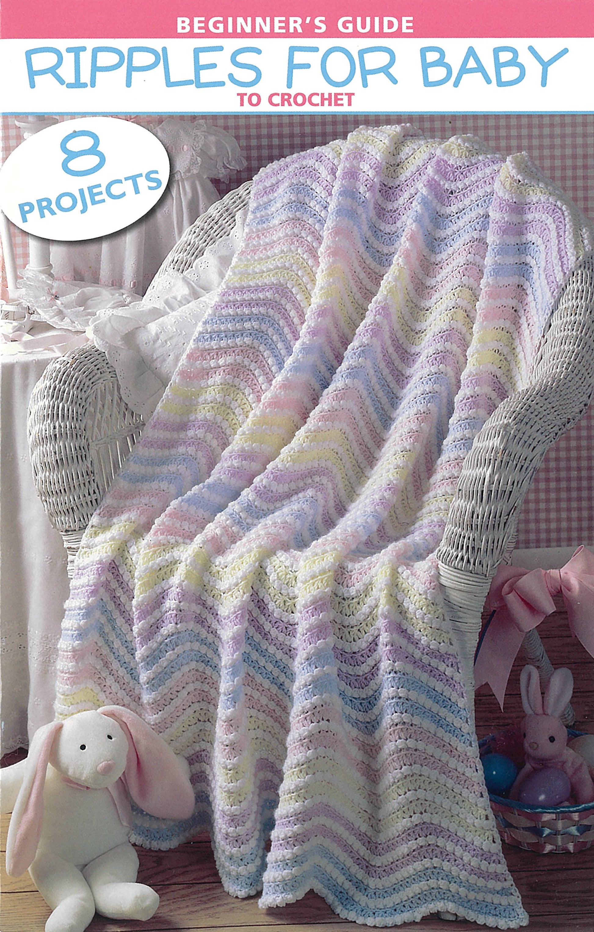 A pastel crocheted blanket drapes over a white wicker chair, with a pink and white stuffed bunny nearby. The image is labeled "Beginner's Guide Ripples For Baby" by Leisure Arts.