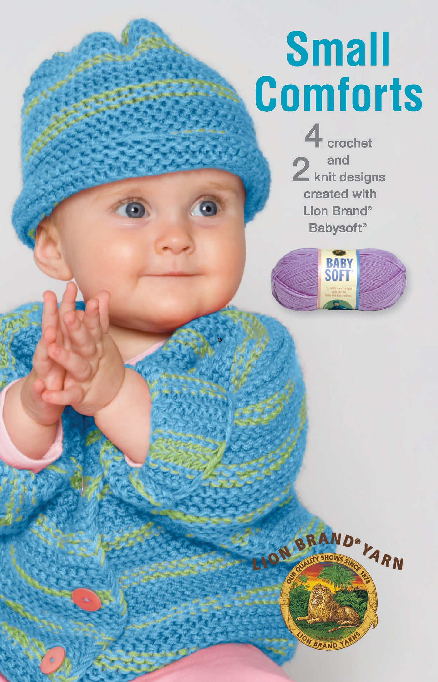 A baby in a blue and green crocheted hat and sweater claps. Text: Small Comforts—4 crochet & 2 knit designs created with Lion Brand Babysoft by Leisure Arts. Shows purple yarn skein and Lion Brand Yarn logo.