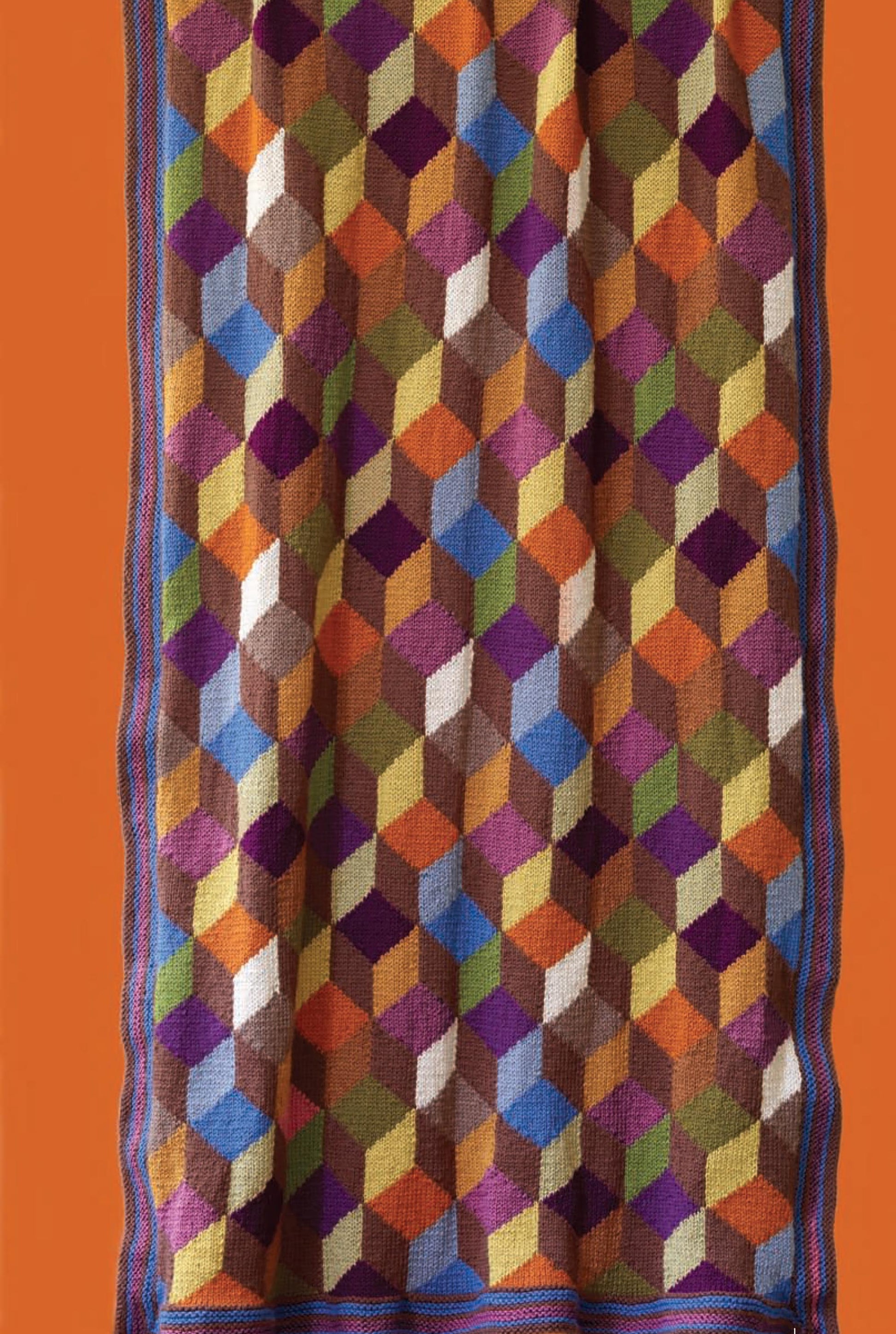 Vanna's Fashions of Knit & Crochet by Leisure Arts features a vibrant 3D cube blanket with blue and purple borders, made from easy-care yarn—a cozy, practical pick for crochet enthusiasts.