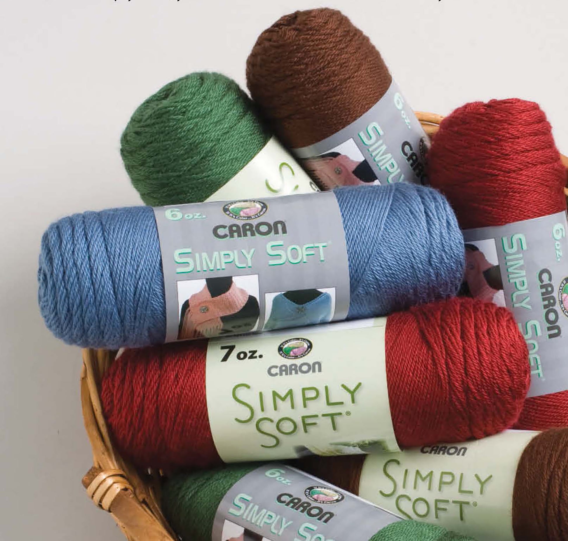 A basket filled with skeins of Leisure Arts Grannies Gone Wild yarn in green, brown, blue, red, and burgundy—perfect for crochet afghans or beginner projects—each skein labeled by weight and brand.
