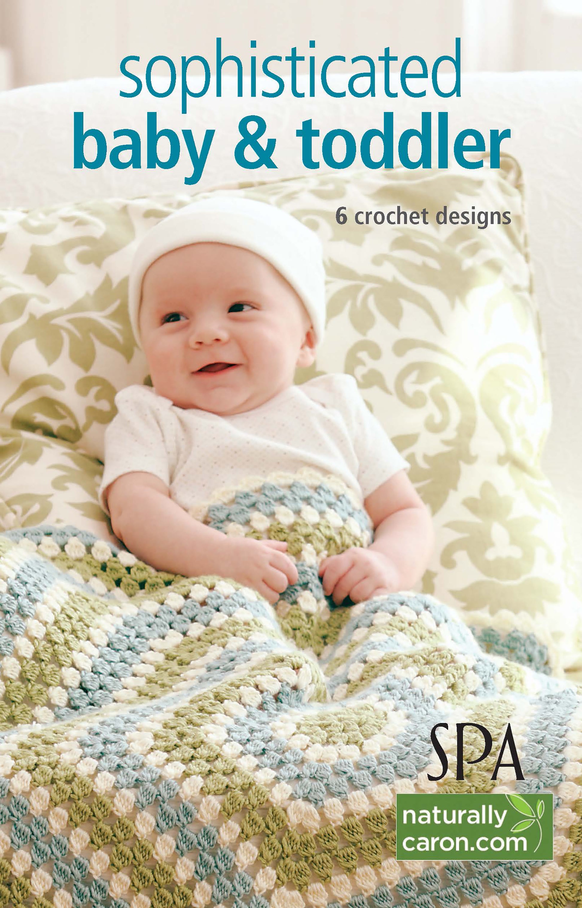A smiling baby in white sits on a patterned cushion, wrapped in a blue, green, and cream blanket. Text: “Sophisticated Babies & Toddlers—6 Crochet Designs Digital Download by Leisure Arts.”.