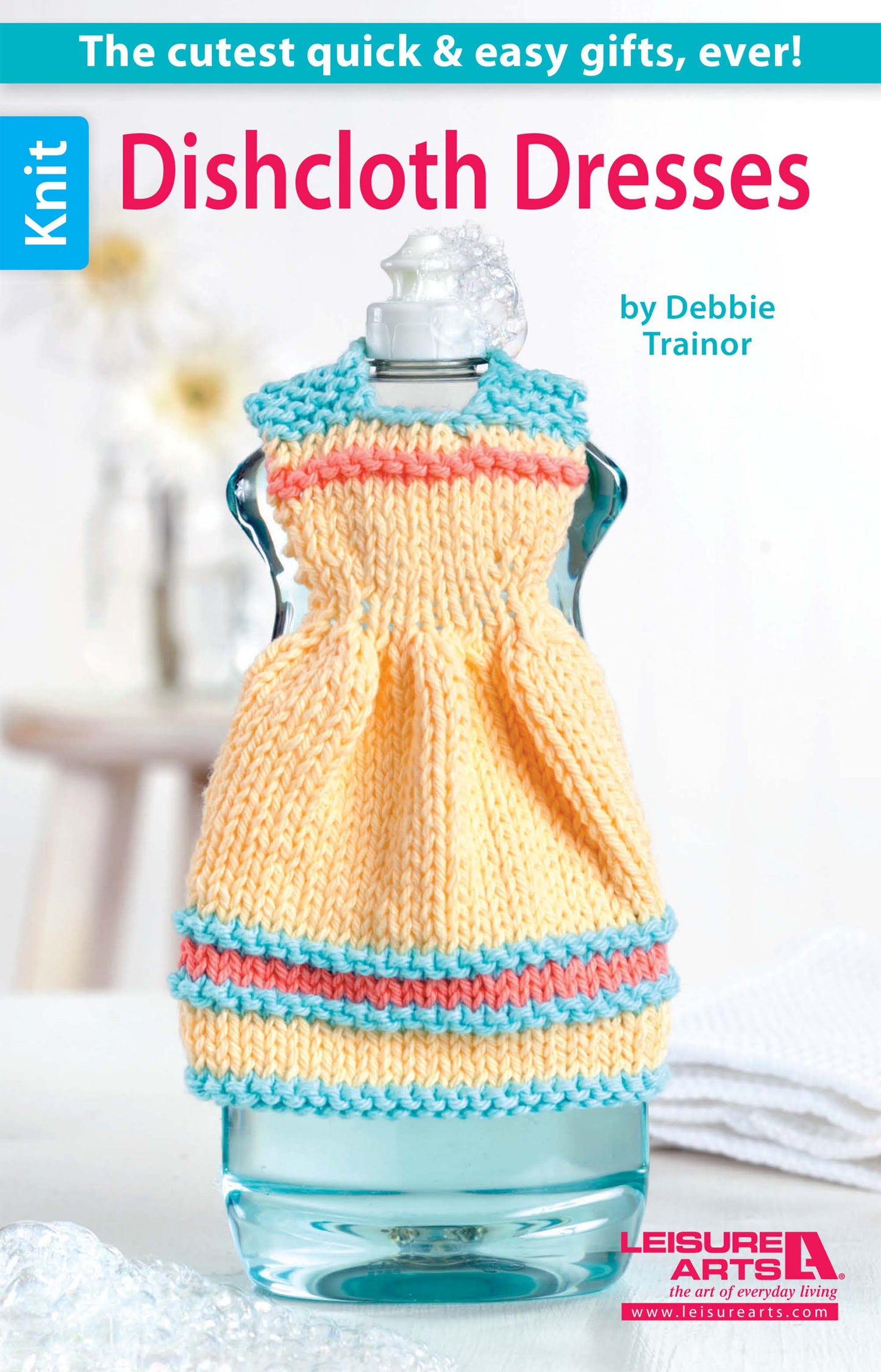 A glass soap bottle wears a yellow cotton yarn dress-shaped cover with blue and pink stripes, as featured on the cover of "Dishcloth Dresses—The Cutest Quick & Easy Gifts, Ever! Digital Download" by Leisure Arts.