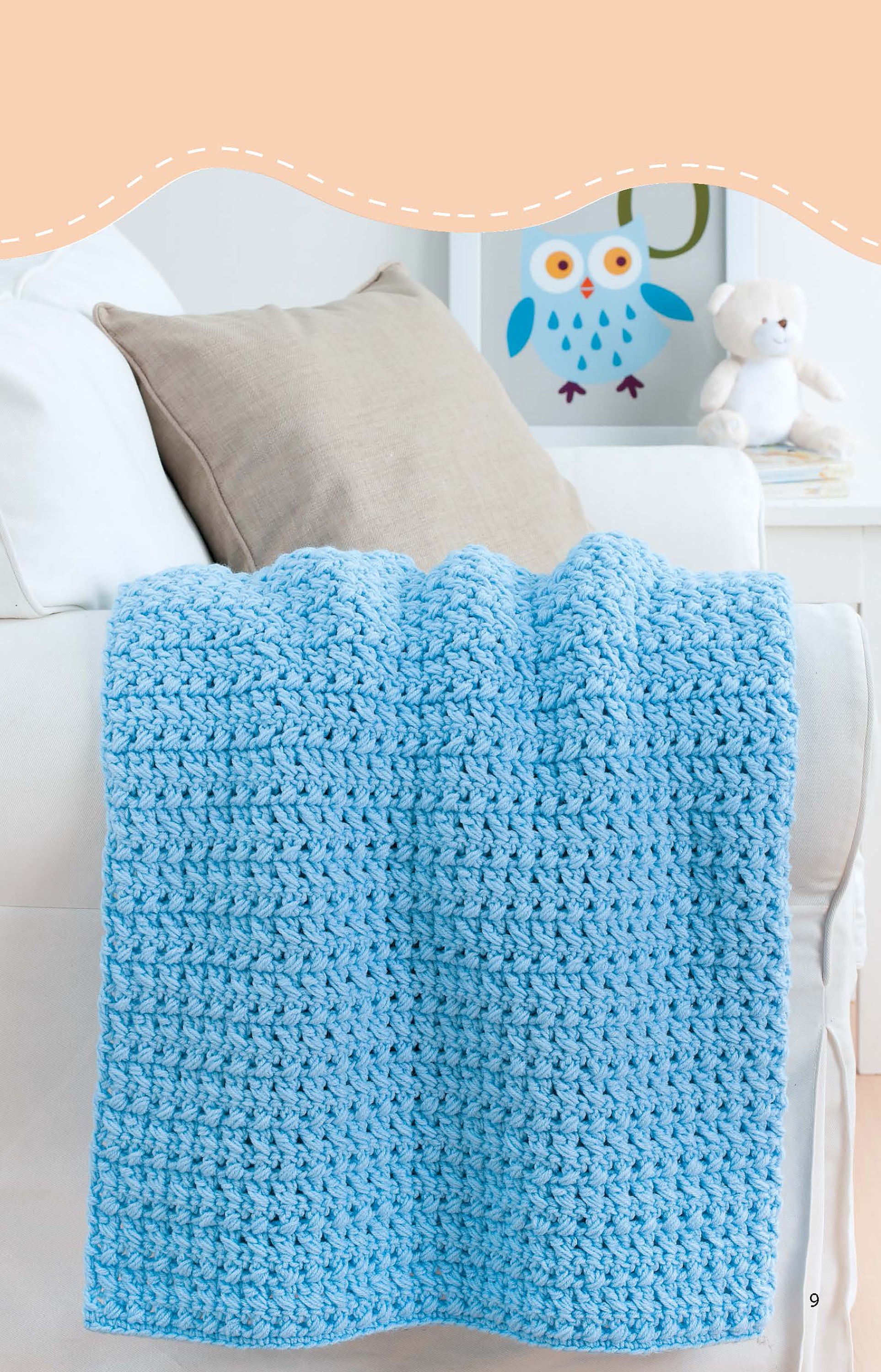 A light blue, medium weight Leisure Arts Crochet Blankets for Toddlers blanket is draped over a white sofa with a beige cushion, with a framed owl illustration and white teddy bear in the background—ideal for easy or beginner crochet blanket projects.