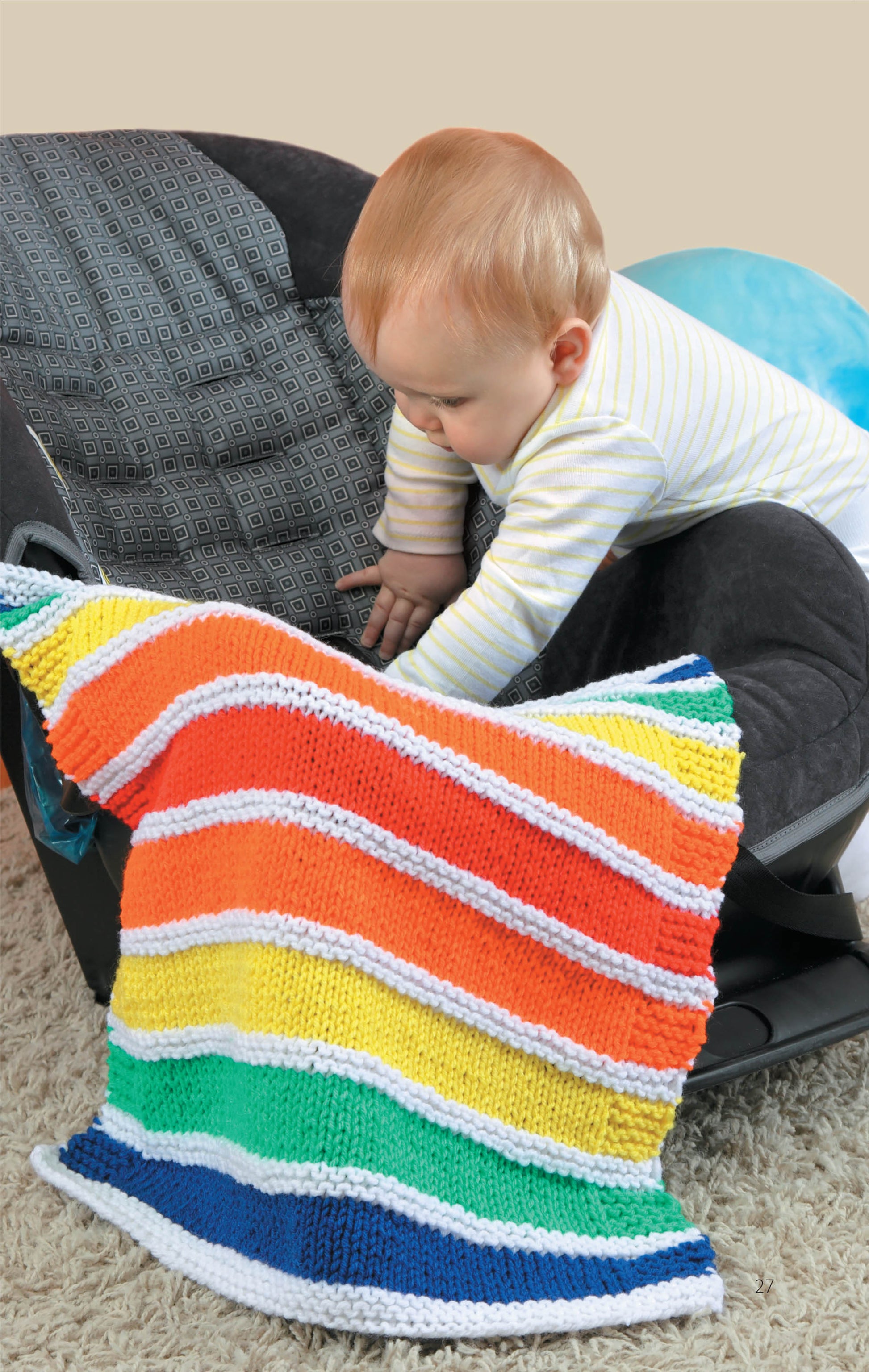 A baby in a striped outfit reaches into a car seat covered by the Leisure Arts Knit Car Seat Blankets—an easy, colorful pattern available as a digital download, perfect for simple knitting projects and thoughtful baby shower gifts.