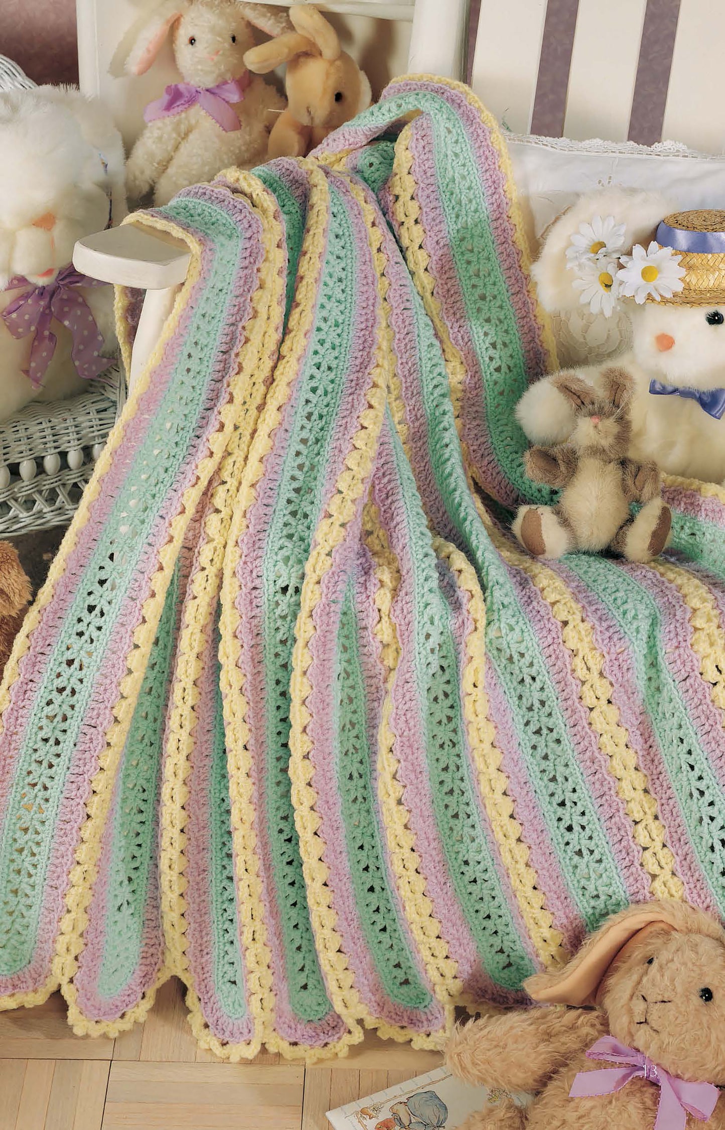 The Learn to Make Mile-a-Minute Baby Afghans Digital Download by Leisure Arts features a pastel crochet blanket with yellow, green, and lavender stripes—ideal for beginners—shown over a white chair with plush bunny and lamb stuffed animals.