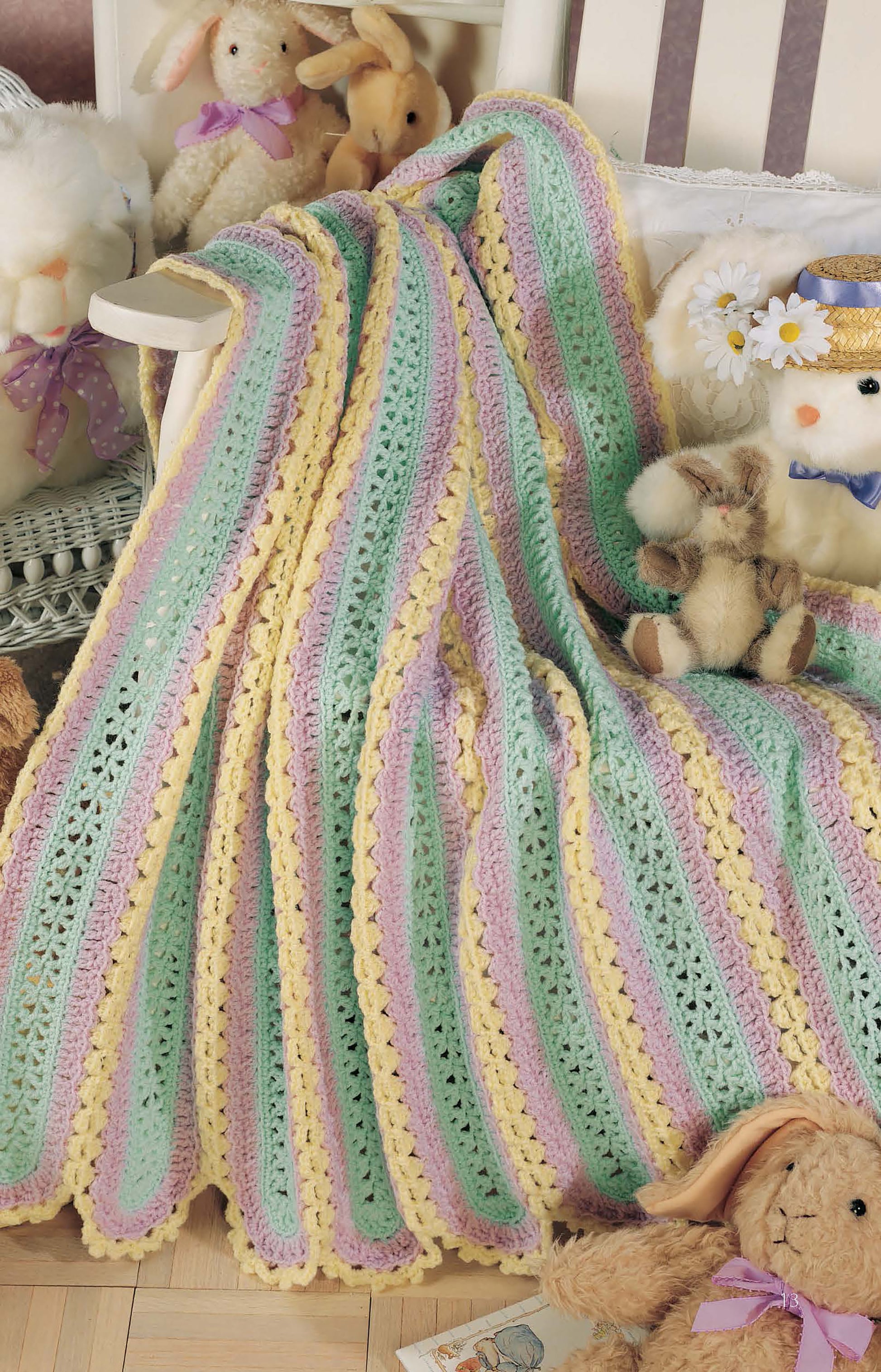 The Learn to Make Mile-a-Minute Baby Afghans Digital Download by Leisure Arts features a pastel crochet blanket with yellow, green, and lavender stripes—ideal for beginners—shown over a white chair with plush bunny and lamb stuffed animals.