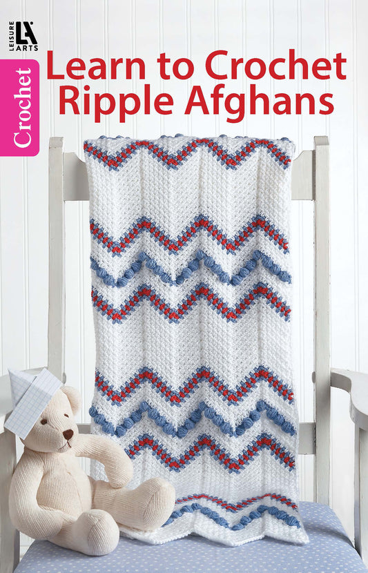 A blue, red, and white crocheted ripple afghan drapes over a chair beside a teddy bear with a blue cap. Text reads: “Leisure Arts Learn to Crochet Ripple Afghans Digital Download—easy ripple patterns included.”.
