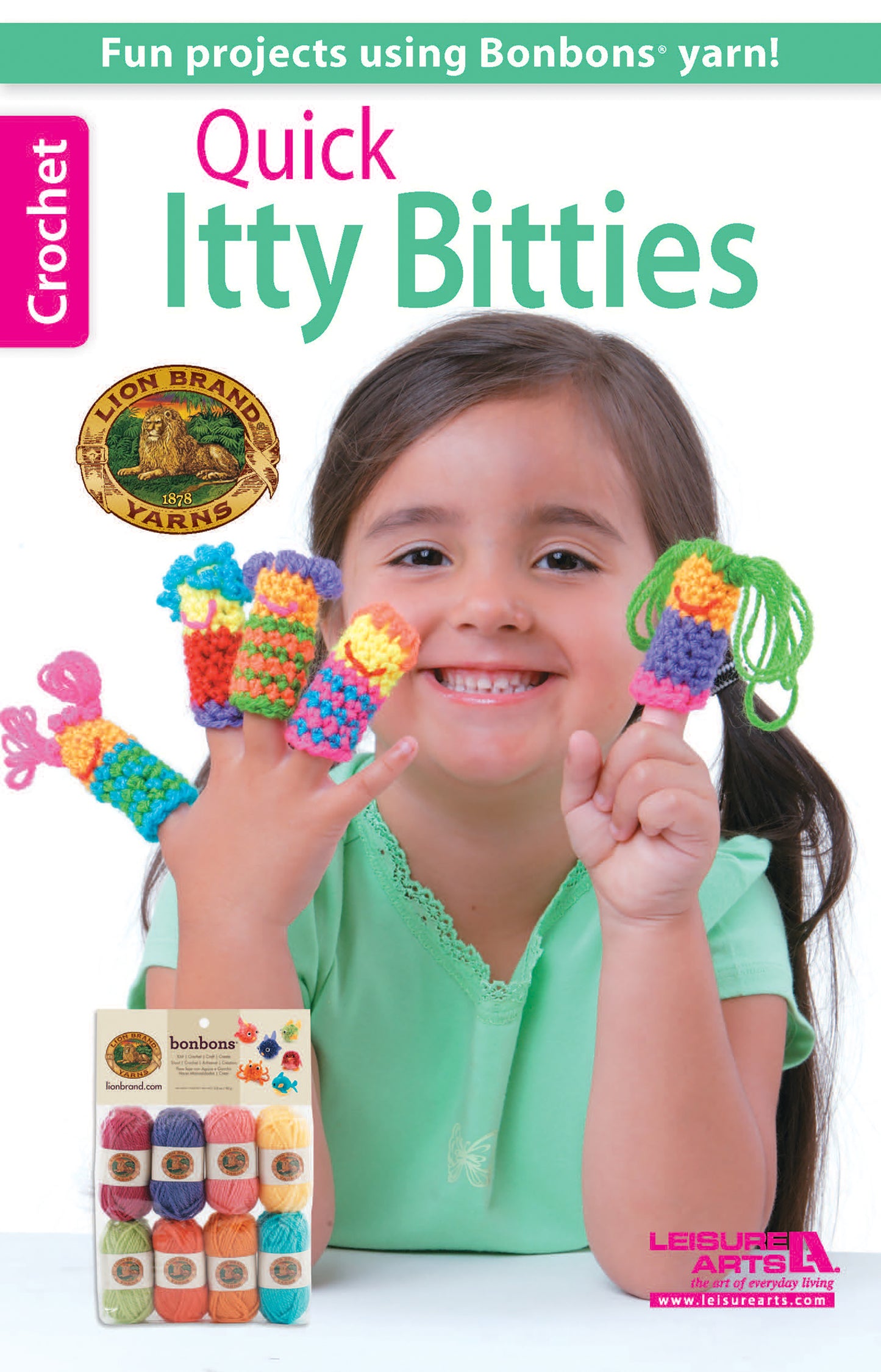 A smiling girl in a green shirt shows off colorful crochet finger puppets on each finger. Beside her is the Quick Itty Bitties Crochet kit from Leisure Arts, making it great for beginner crochet projects.