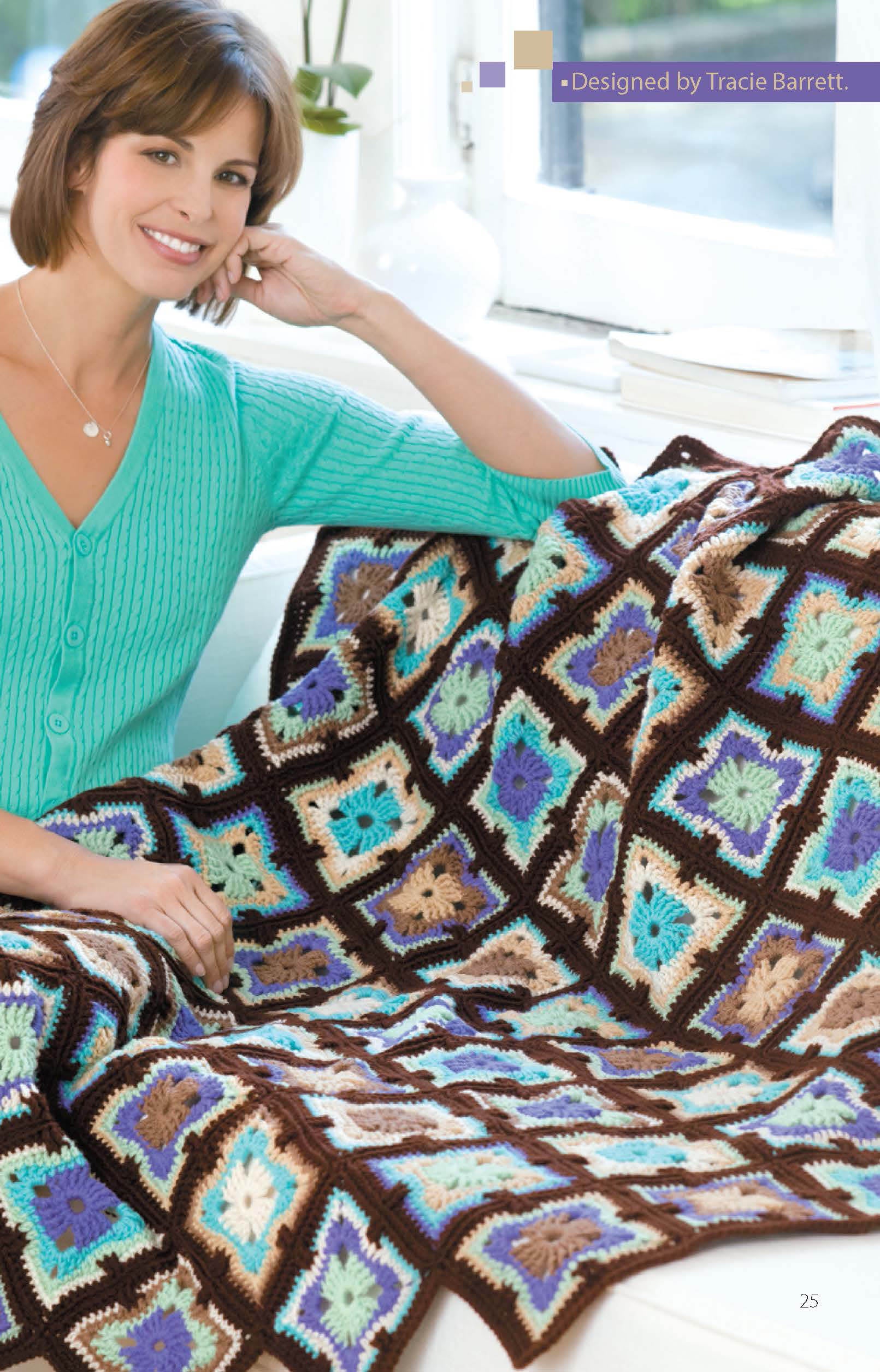 A woman in a turquoise sweater sits on a white couch, smiling while holding a colorful Crochet Throws Worked in the Round afghan from Leisure Arts—an easy to intermediate digital pattern in blue, brown, cream, and purple.