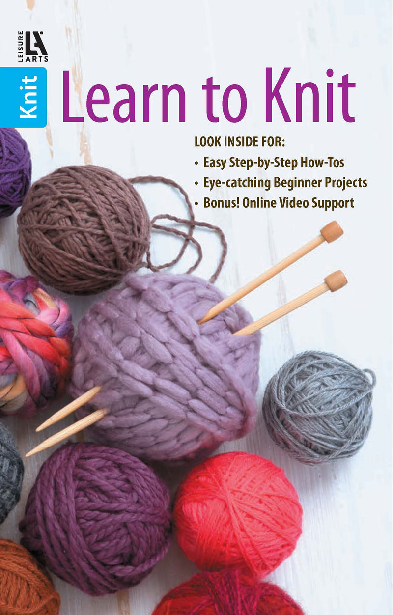 A variety of colorful yarn balls, super bulky yarn, and two wooden knitting needles are displayed. The image promotes Leisure Arts’ Learn to Knit—Easy Step-by-Step How-Tos, Eye-Catching Beginner Projects Digital Download.