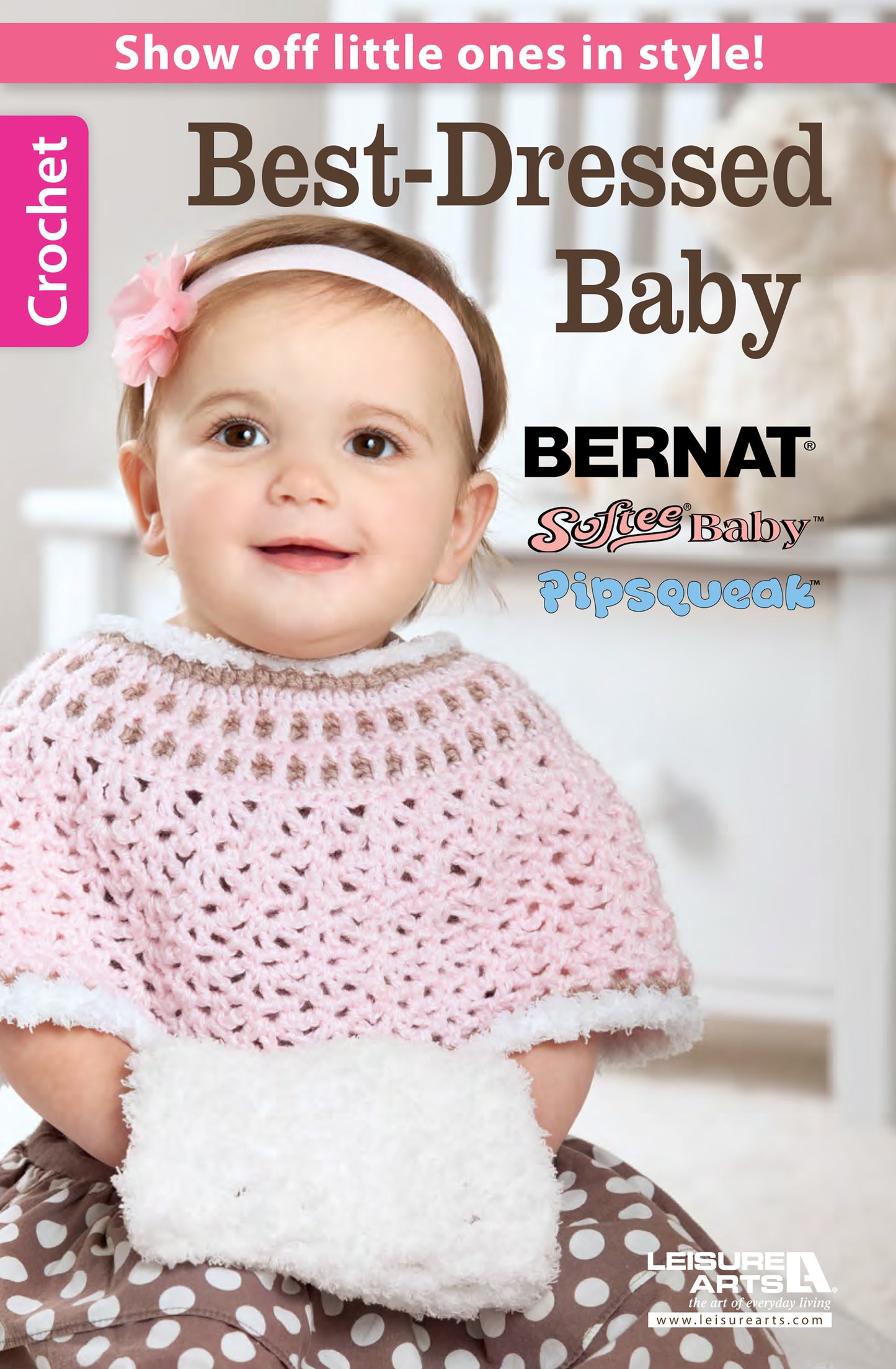 A smiling baby wears a pink and white crocheted cape, floral headband, and mittens. The image promotes cute outfits from the Best-Dressed Baby Crochet Digital Download by Leisure Arts, featuring charming crochet patterns for little ones.