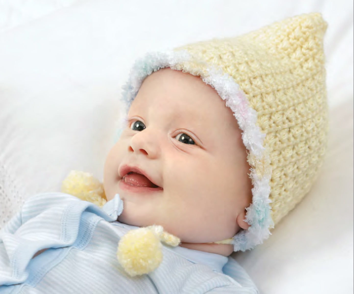 A smiling baby in cozy crochet, inspired by Leisure Arts’ Best-Dressed Baby Crochet Digital Download—perfect for your next adorable stitch guide or baby outfit creation.