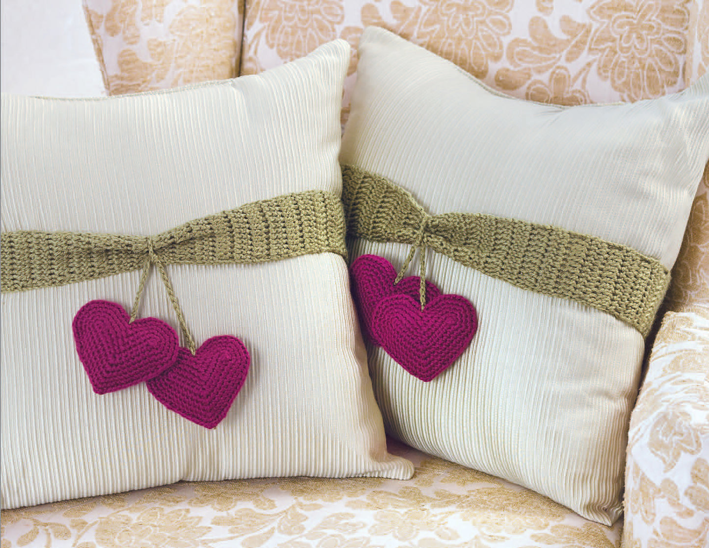 Pillow Fun—Playful Accents for Your Home! by Leisure Arts features two cream pillow sets with olive green bands and magenta hearts, arranged on a floral chair to highlight trendy colors and whimsical style.