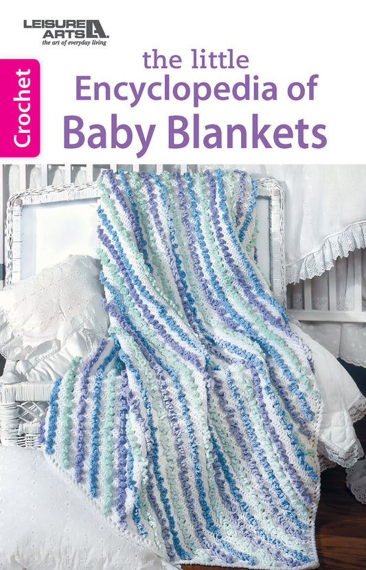 A crocheted baby blanket with blue, green, and purple stripes drapes over a white chair beside a crib. The cover reads The Little Encyclopedia of Crocheted Baby Blankets by Leisure Arts and features crochet patterns on the spine.