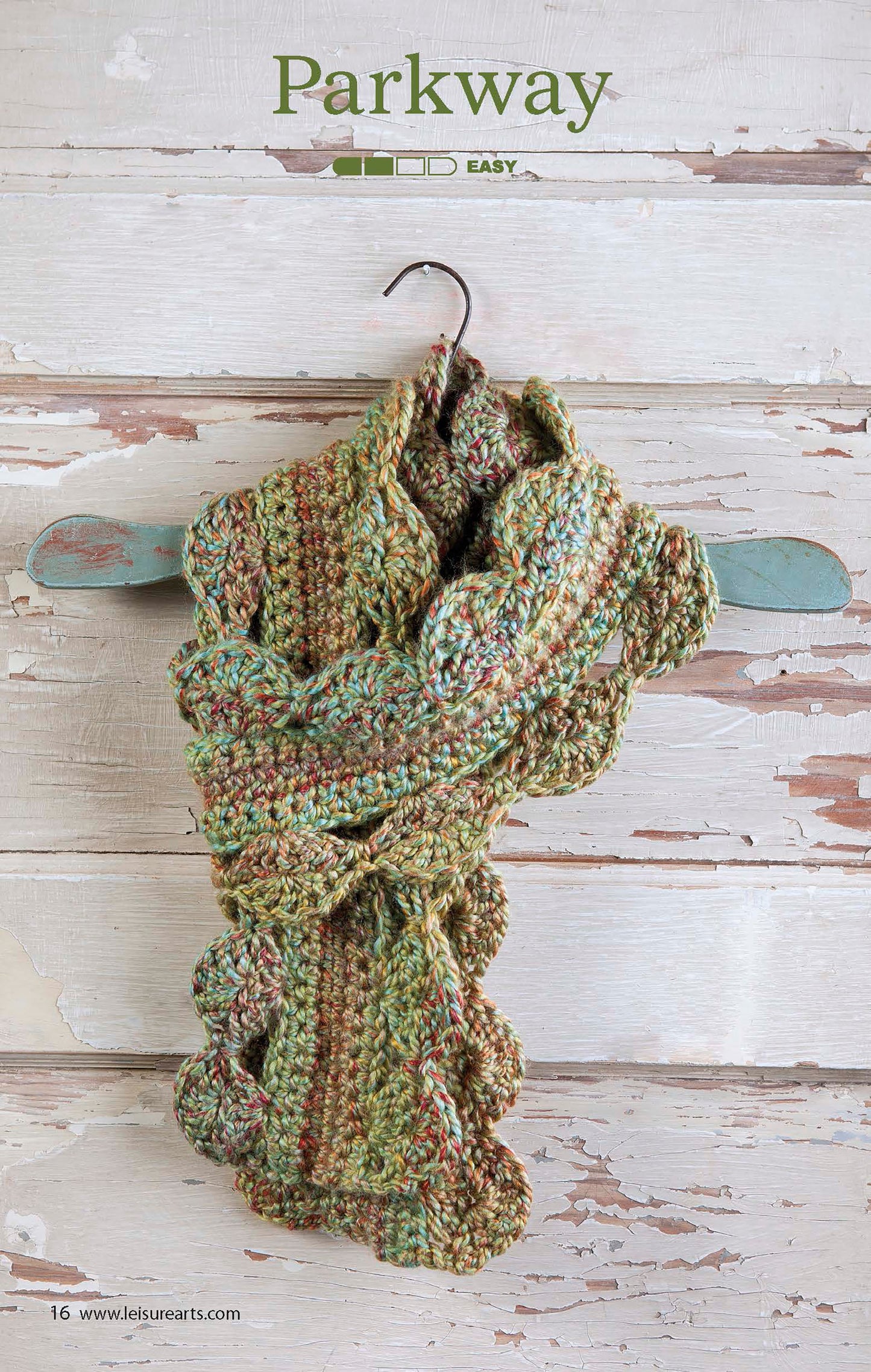 A textured, multicolored crochet scarf with scalloped edges hangs on a rustic hook against weathered white wood. Text at the top reads The Little Encyclopedia of Crocheted Scarves by Leisure Arts, ideal for beginner crochet enthusiasts.