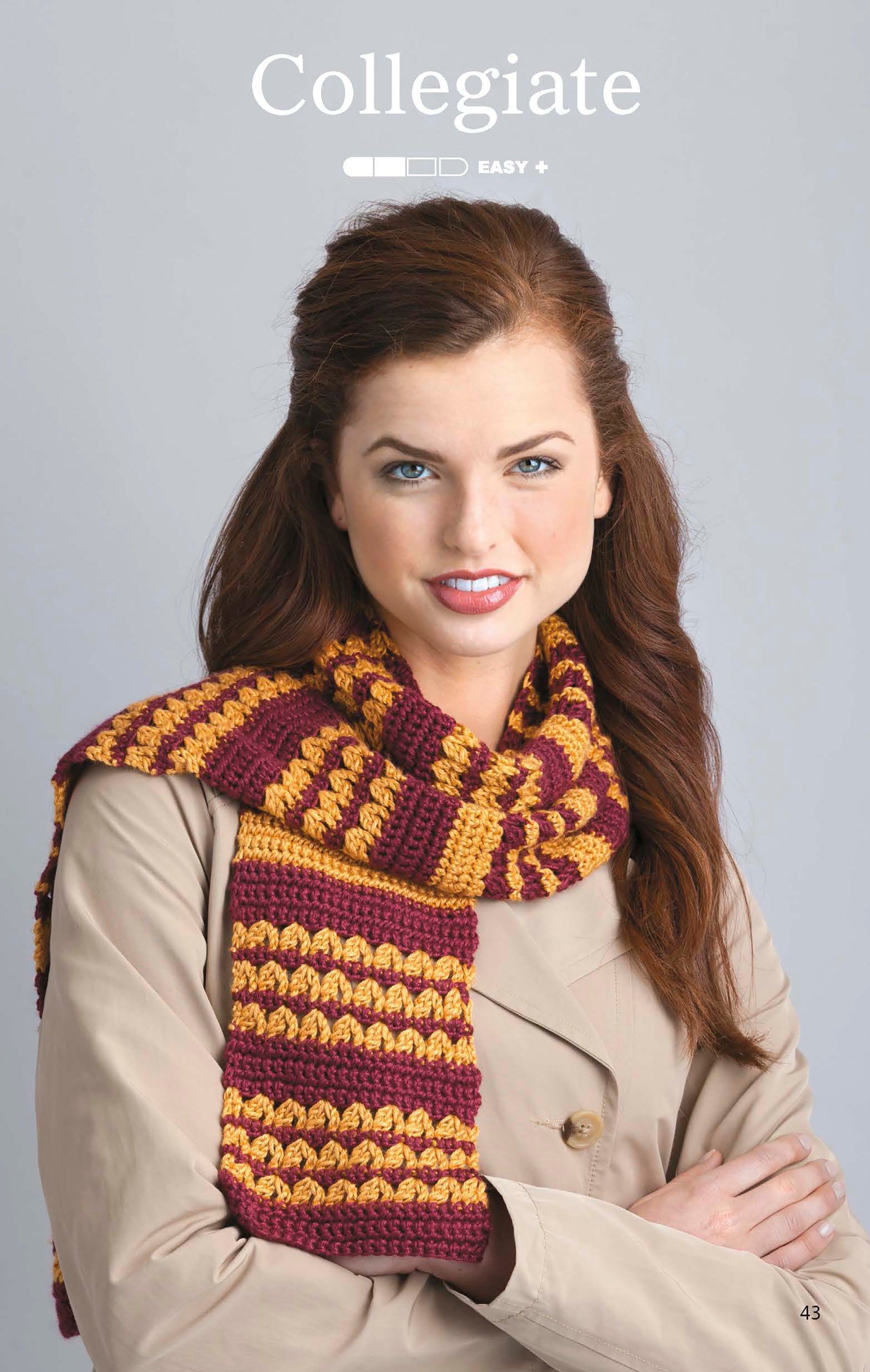 A woman in a beige coat models a maroon and gold striped crochet scarf from "The Little Encyclopedia of Crocheted Scarves" by Leisure Arts, ideal for beginners. She smiles softly against a light gray background under the word “Collegiate.”.