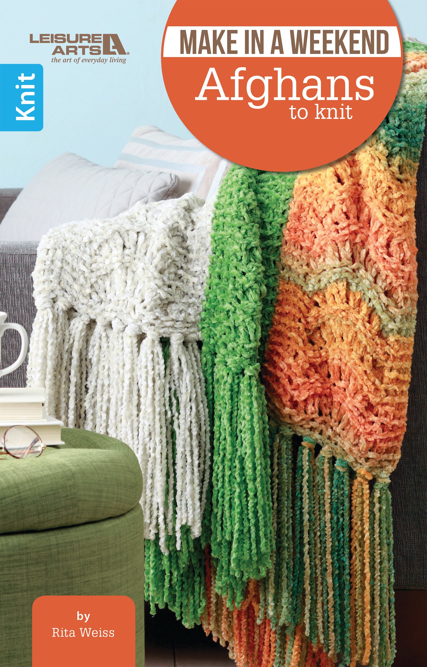 Cover of "Make in a Weekend Afghans to Knit" by Leisure Arts shows two colorful knit afghans on a couch beside a green ottoman and white mug—ideal for quick, easy weekend projects.