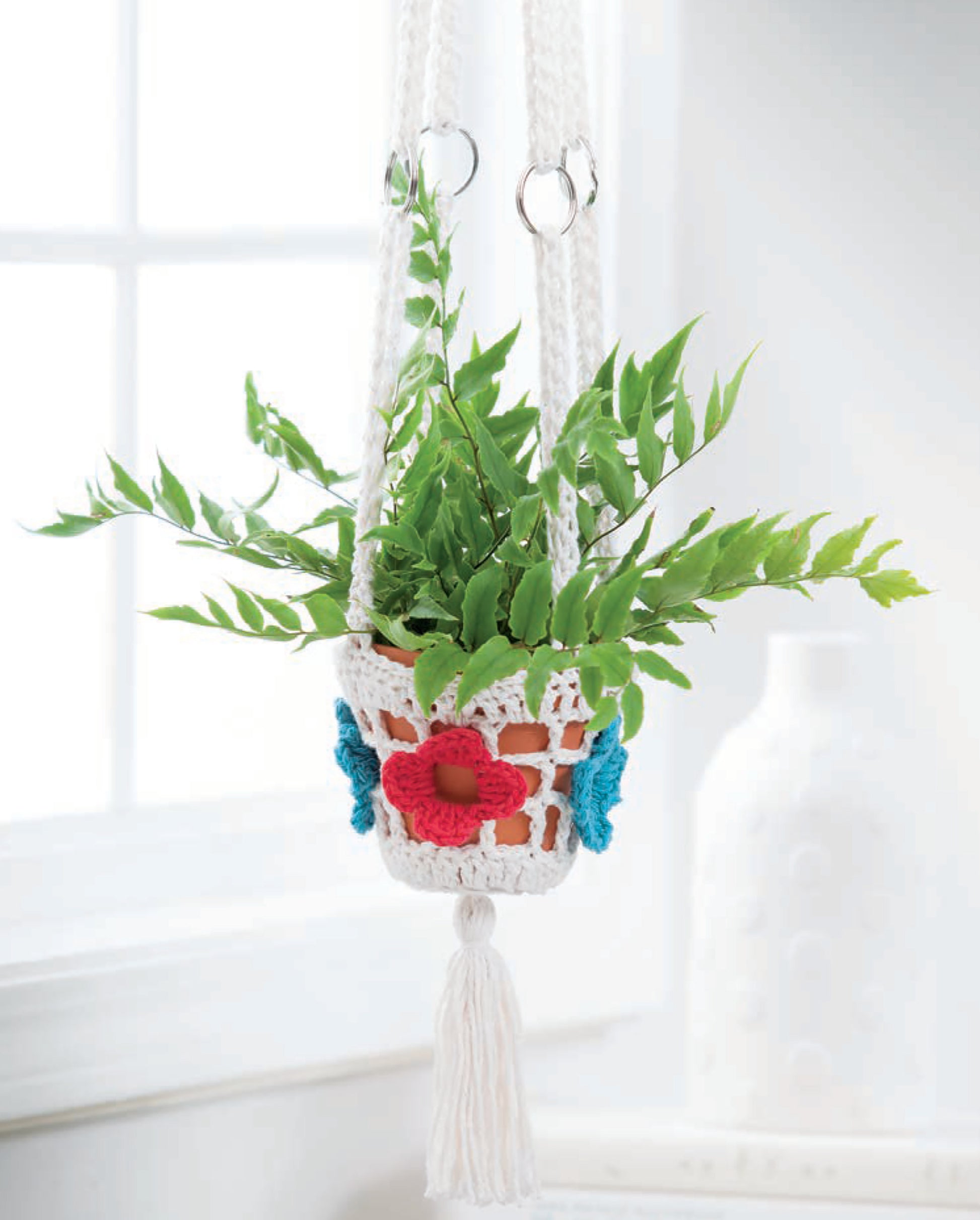 Display your potted plants in style with Pretty Little Plant Hangers by Leisure Arts—crochet plant hangers adorned with colorful flowers, perfect for hanging indoors near a window and showcasing creative patterns.
