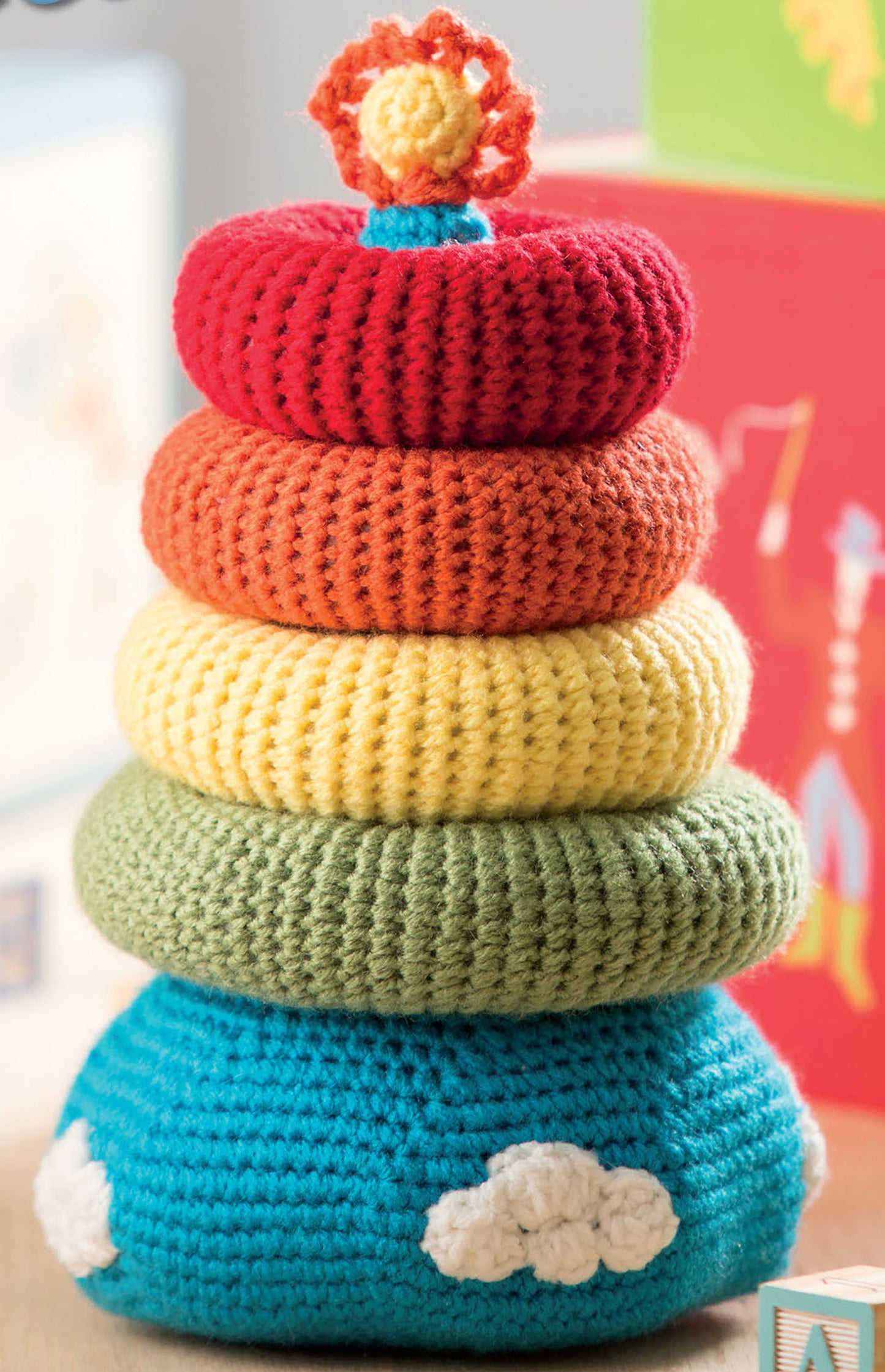 Baby Stacks—6 Easy Toys to Crochet! by Leisure Arts features a colorful stacker toy with blue, green, yellow, orange, and red rings topped with a sun and clouds. Ideal for decorating nurseries or inspiring beginner crochet projects.