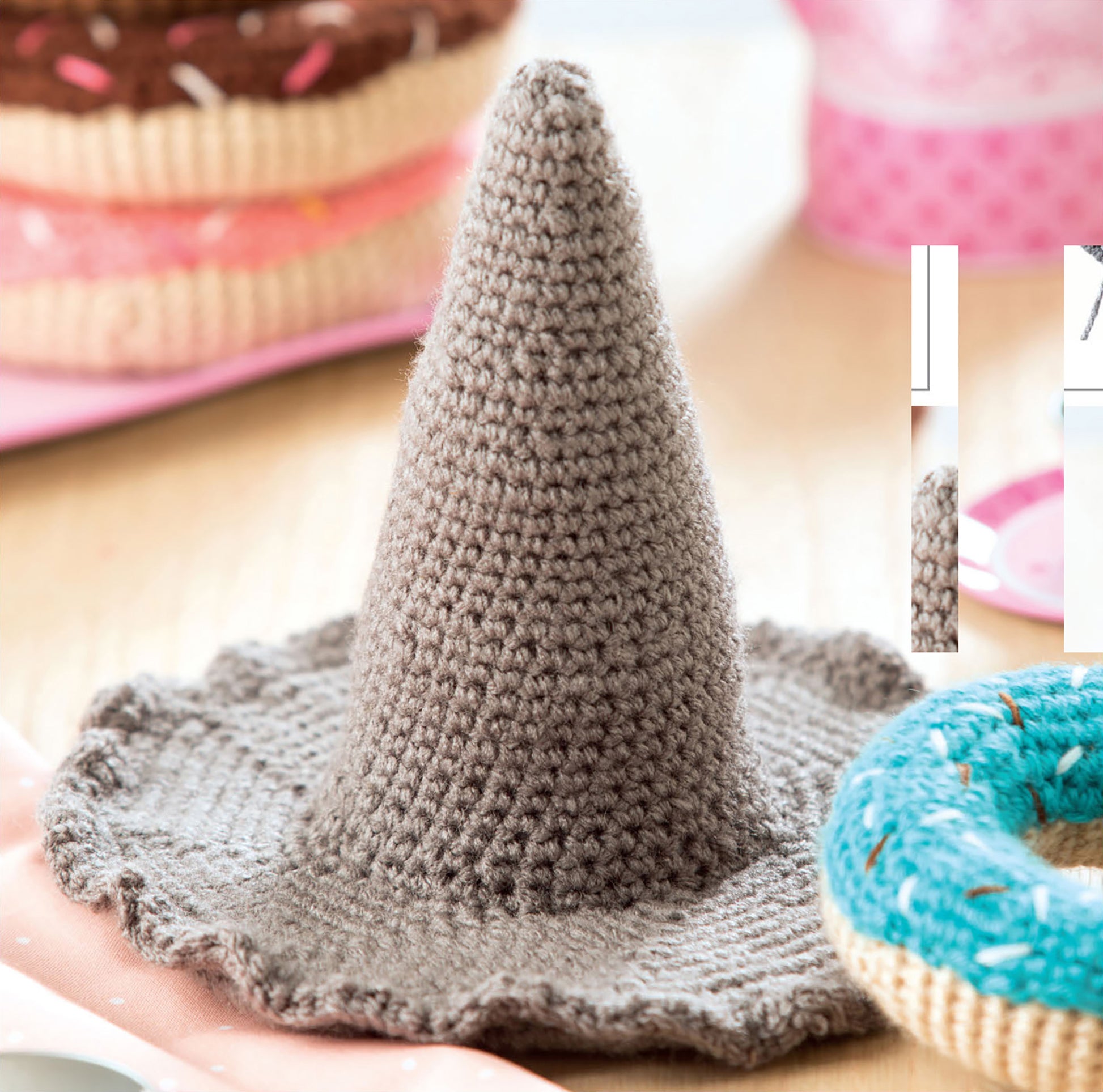 The Baby Stacks—6 Easy Toys to Crochet! kit by Leisure Arts features colorful crochet toys resembling donuts, displayed with a gray witch hat—perfect for inspiring beginner-friendly crochet designs and playful decor.