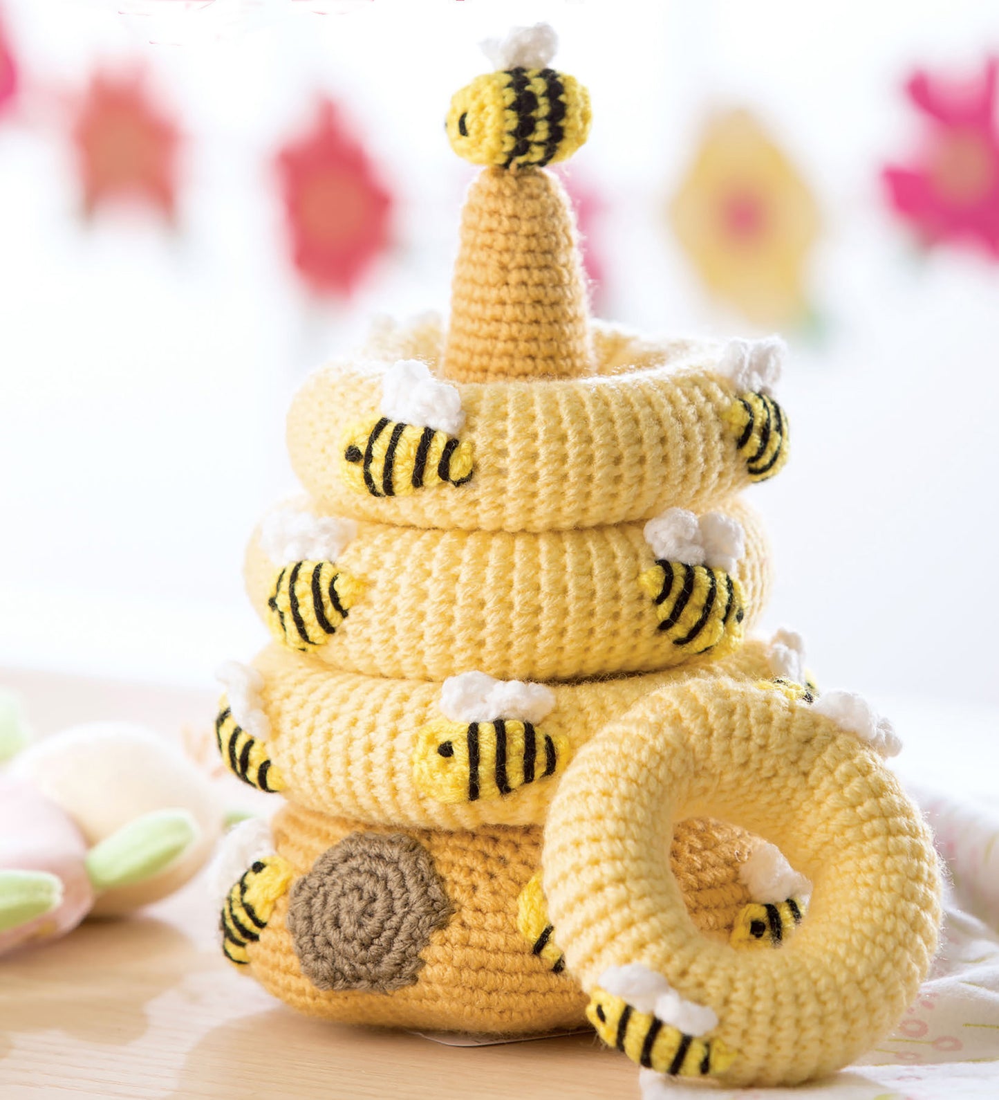 Baby Stacks—6 Easy Toys to Crochet! by Leisure Arts features a beehive-shaped crocheted stacking toy with yellow and black striped rings, white wings, plush bees, and a bee topper—perfect for baby crochet toys or beginner-friendly projects.