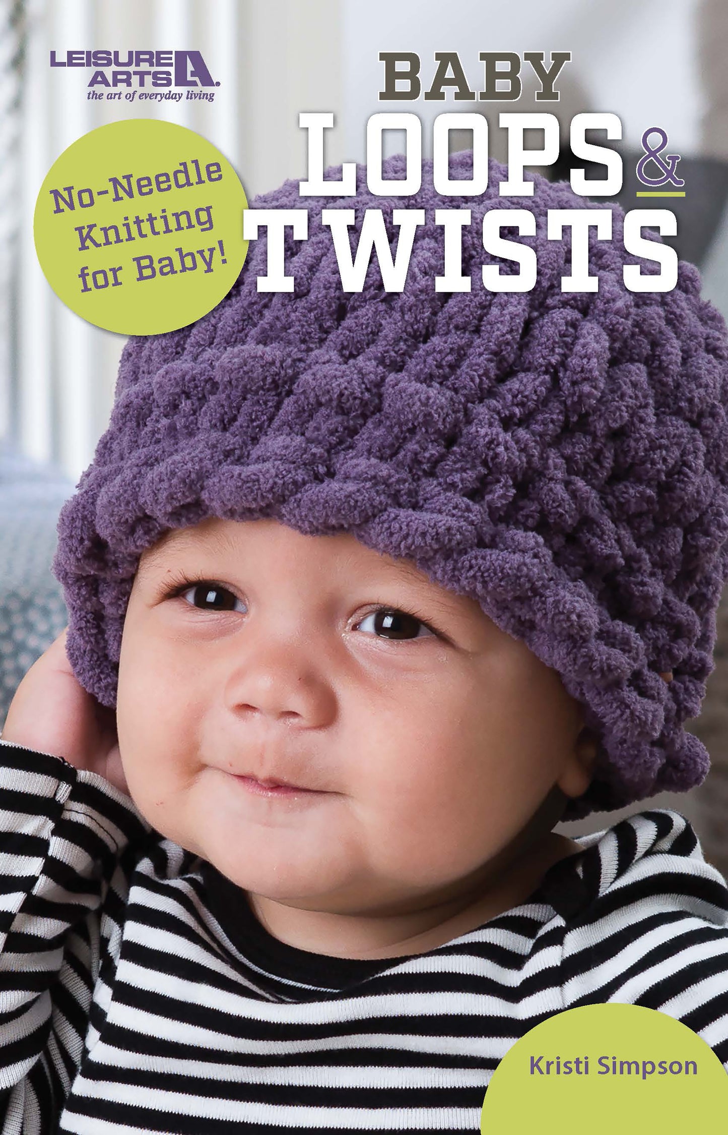 A smiling baby in a purple, chunky, knitted hat made with loop yarn. Baby Loops & Twists—No-Needle Knitting for Baby! by Leisure Arts is perfect for beginner-friendly baby knitting projects and fun patterns.