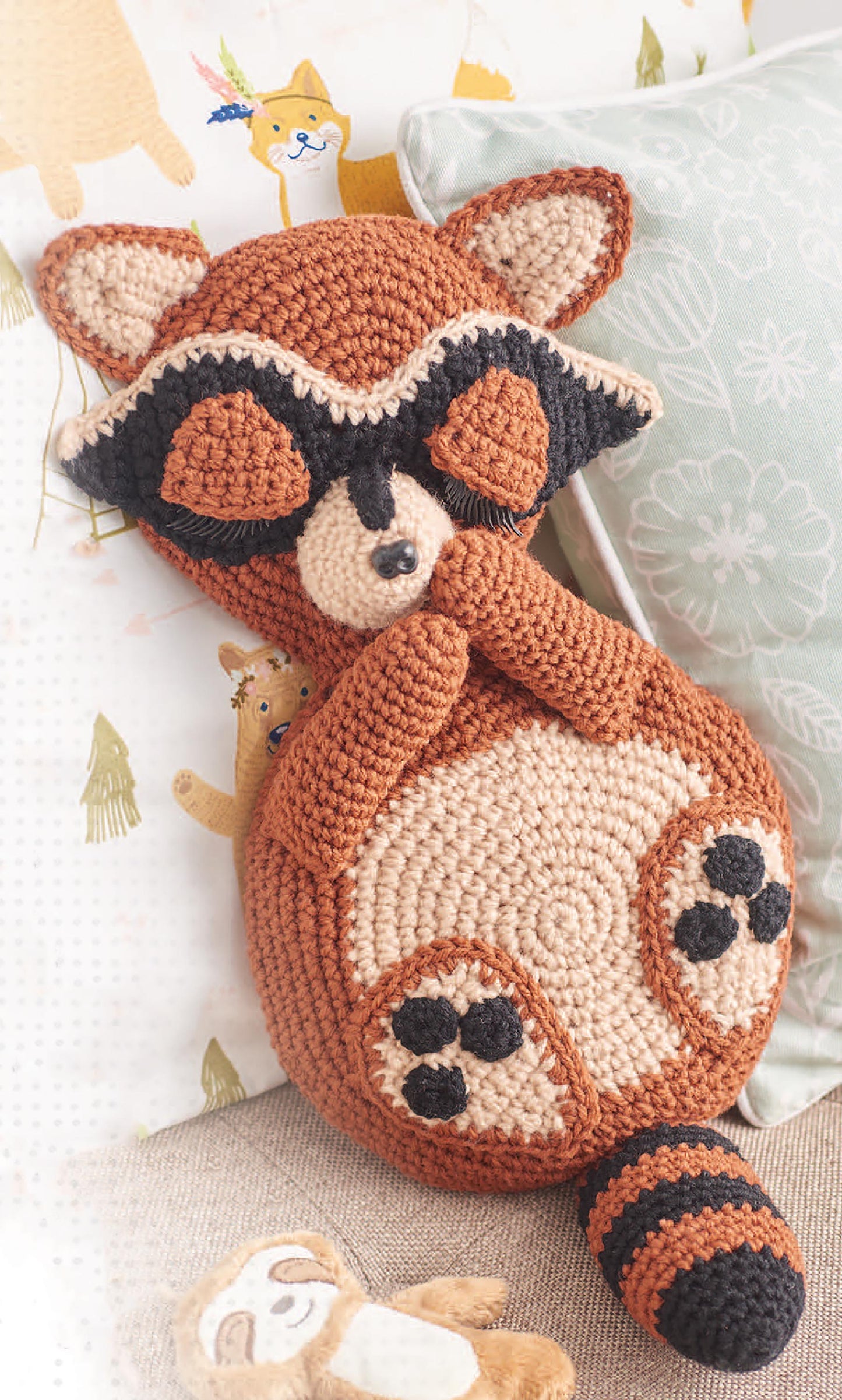 The Cuddle Buddies Crochet from Leisure Arts is a beginner-friendly red panda stuffed toy with closed eyes, a striped tail, and paw details—perfect for anyone wanting to crochet their own adorable animal.