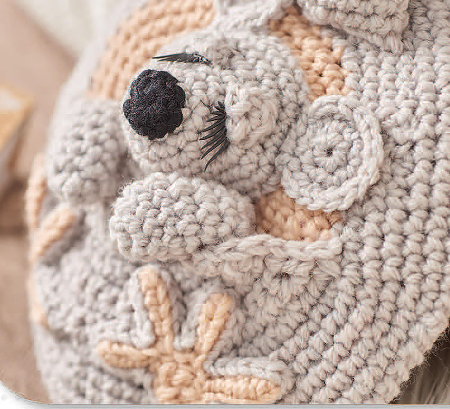 A close-up of a crocheted koala bear with closed eyes and beige accents, created with Cuddle Buddies Crochet by Leisure Arts—a great choice for beginners wanting to craft adorable animals using soft, chunky yarn.