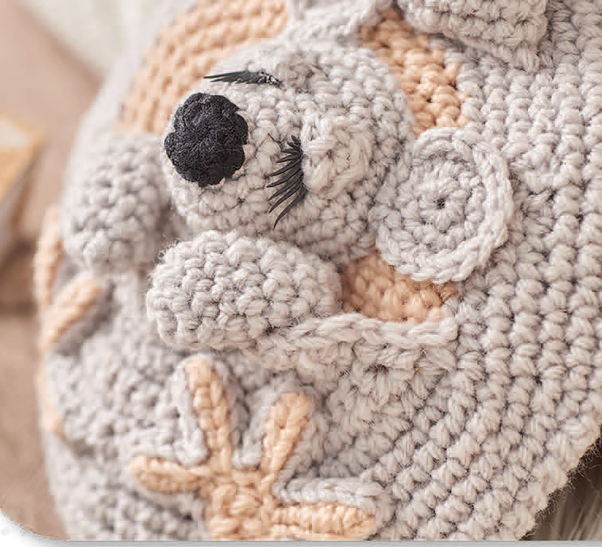 A close-up of a crocheted koala bear with closed eyes and beige accents, created with Cuddle Buddies Crochet by Leisure Arts—a great choice for beginners wanting to craft adorable animals using soft, chunky yarn.