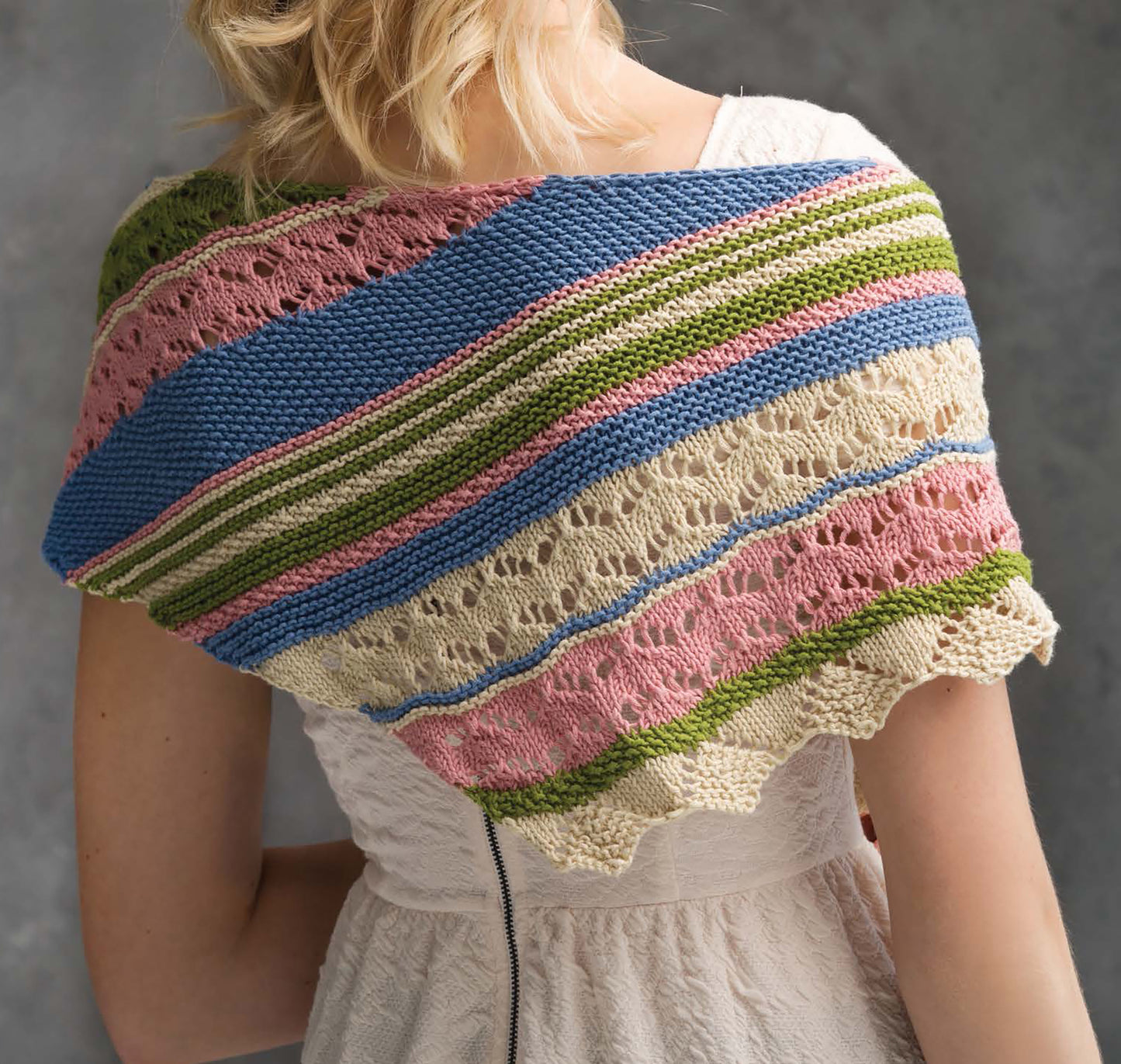 A woman in a white dress models a vibrant striped shawl, featuring textured and lacy patterns—an inspiring easy project from Best of Knit Accessories Digital Download by Leisure Arts.