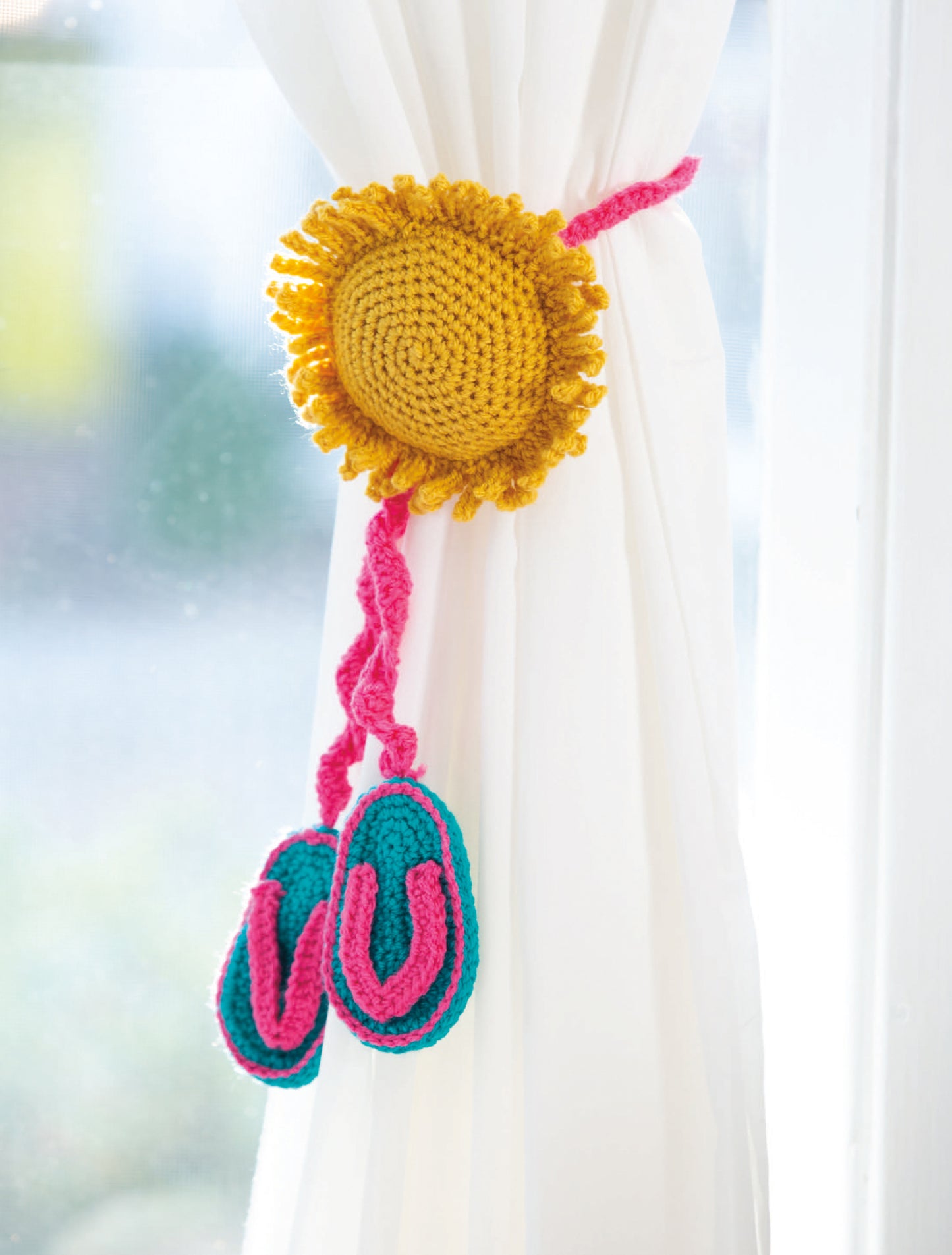 Leisure Arts' Huggable Tie Backs feature a crocheted yellow sun, pink cord, plus blue and pink mini flip-flops—fun DIY accents that add playful charm to your home decor and are ideal beginner crochet projects.